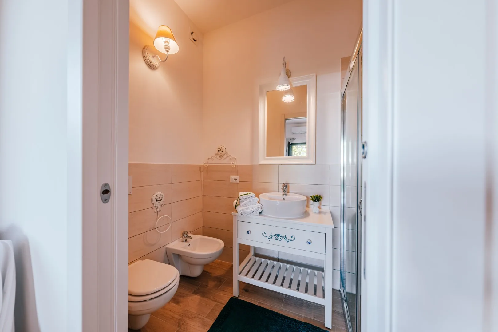 A bathroom with a sink, mirror, toilet, and shower.