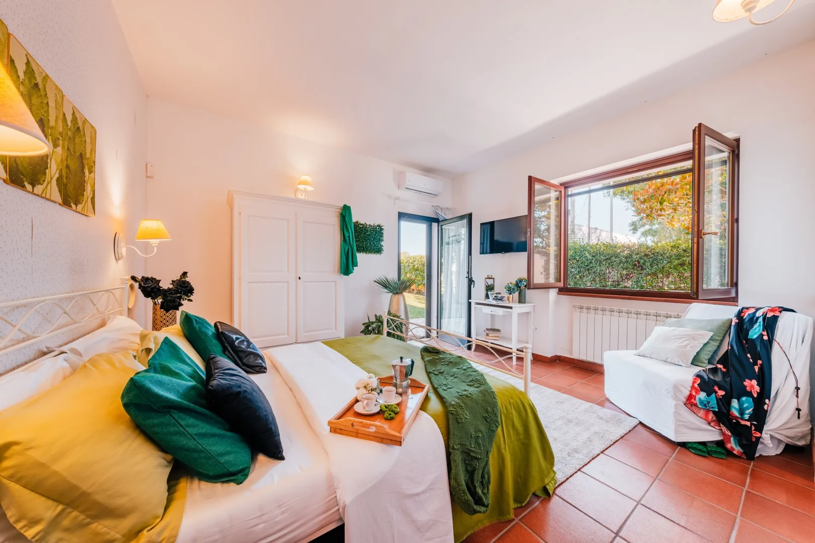 A bright bedroom with a bed, seating, and an open window.