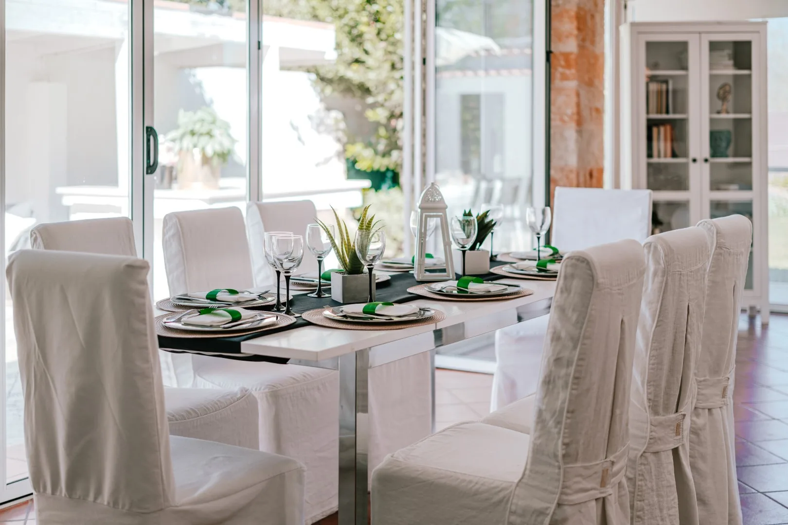 A bright dining area has a set table beside large windows.