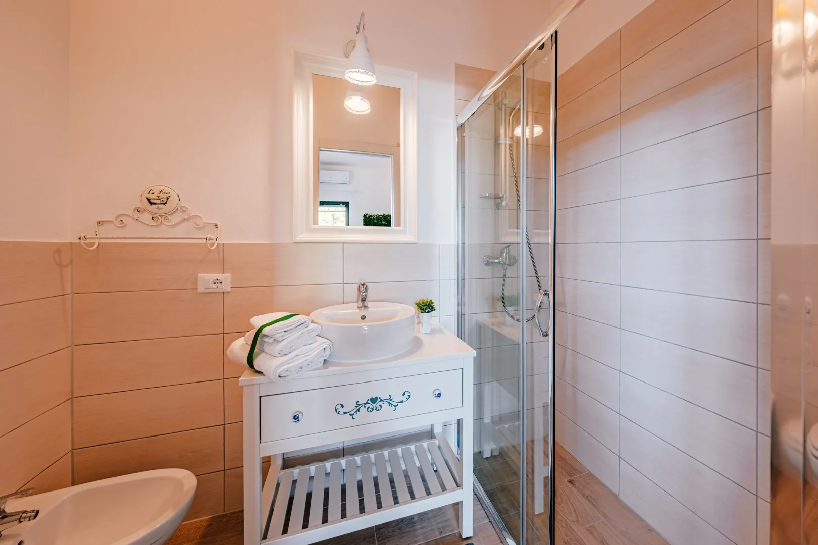 A tiled bathroom with a sink, mirror, and glass shower.