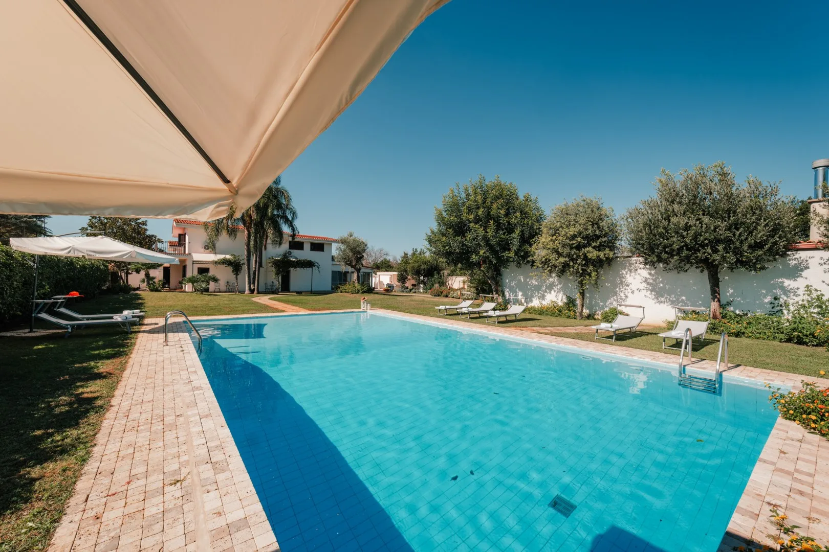 A swimming pool with a shaded seating area beside it.