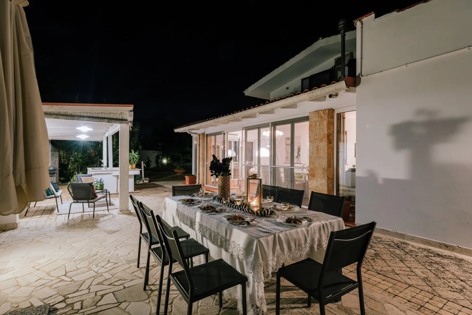 An outdoor dining area at night, with a table set beside the illuminated building.