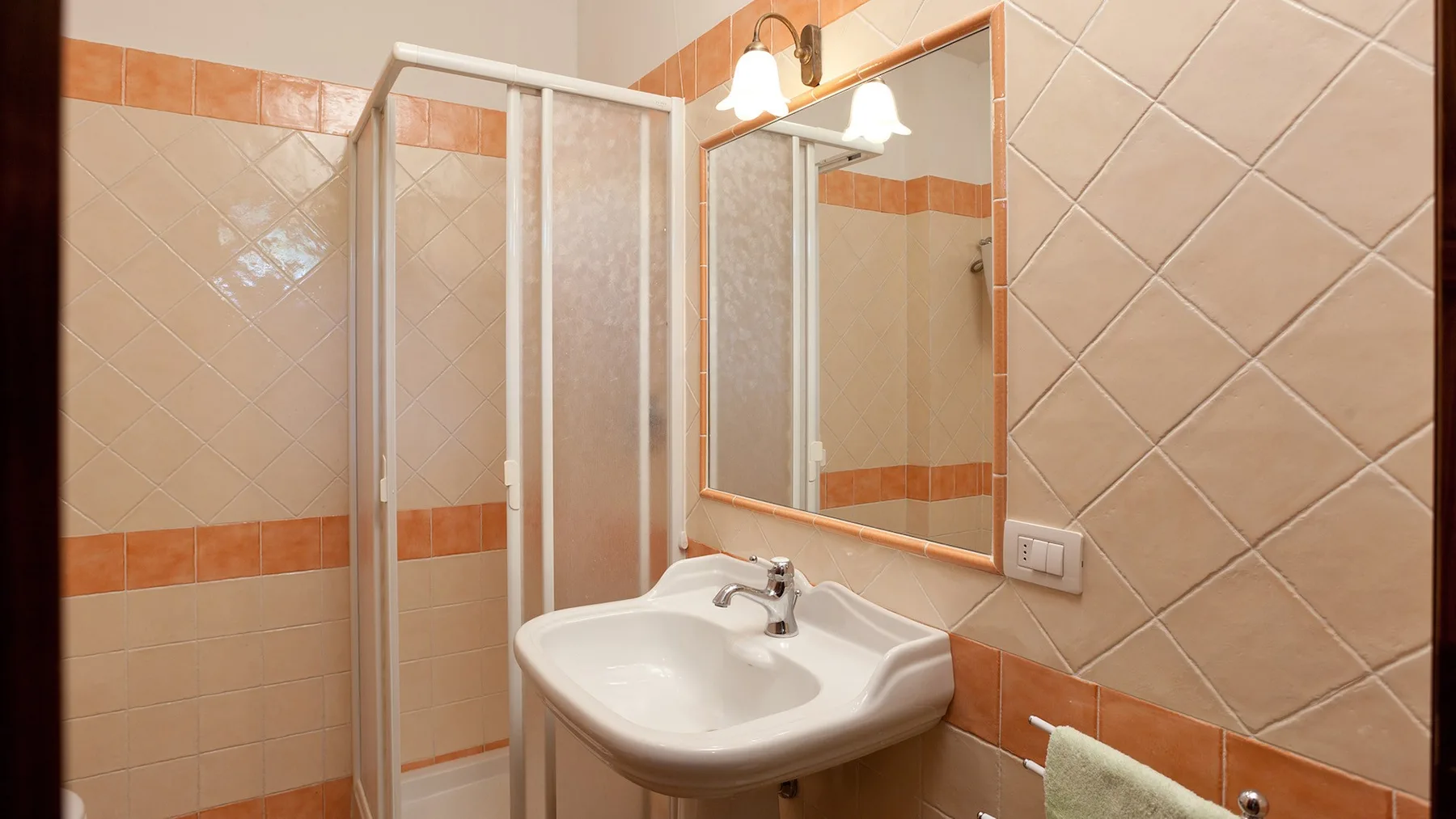 A tiled bathroom with a sink, mirror, and shower.