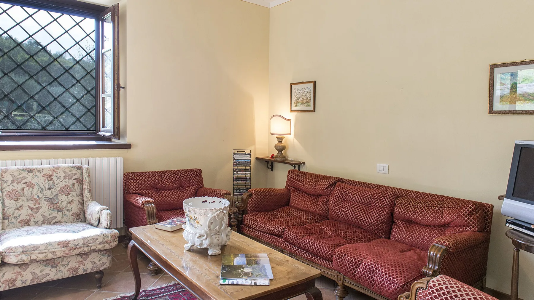 A living room with red seating, a coffee table, and a window.