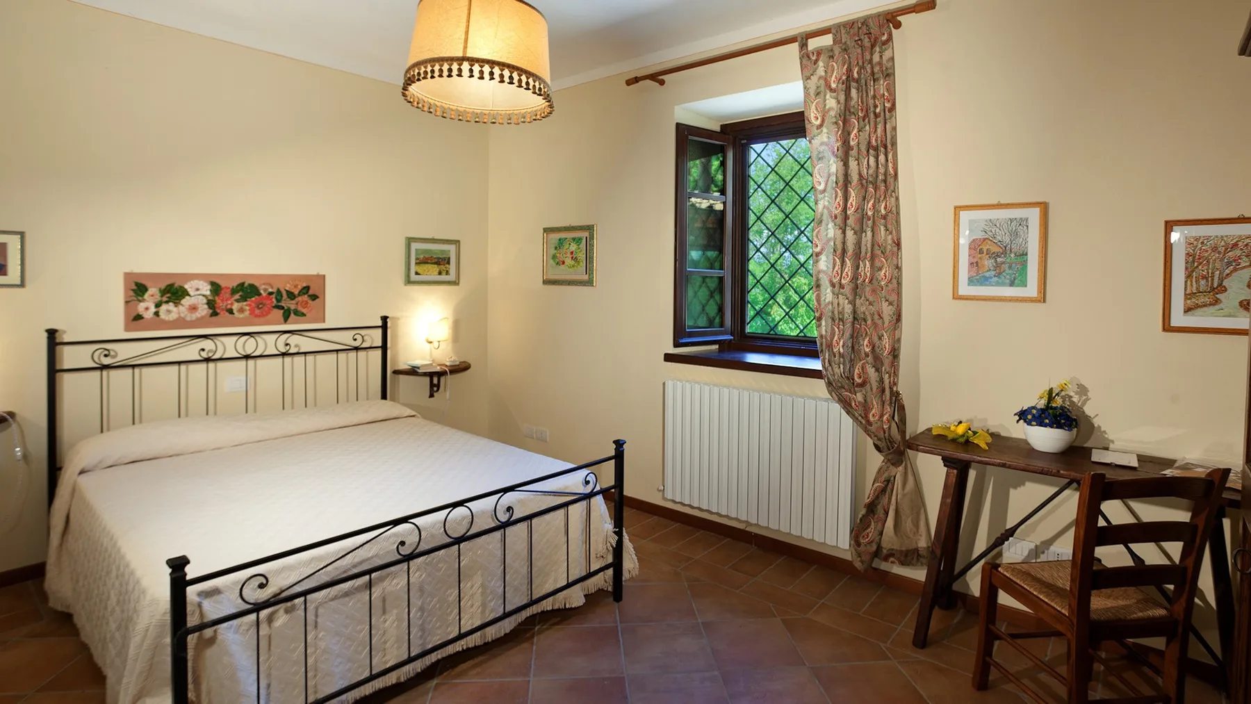 A bedroom with a metal bed, patterned curtains, and a small table by the window.