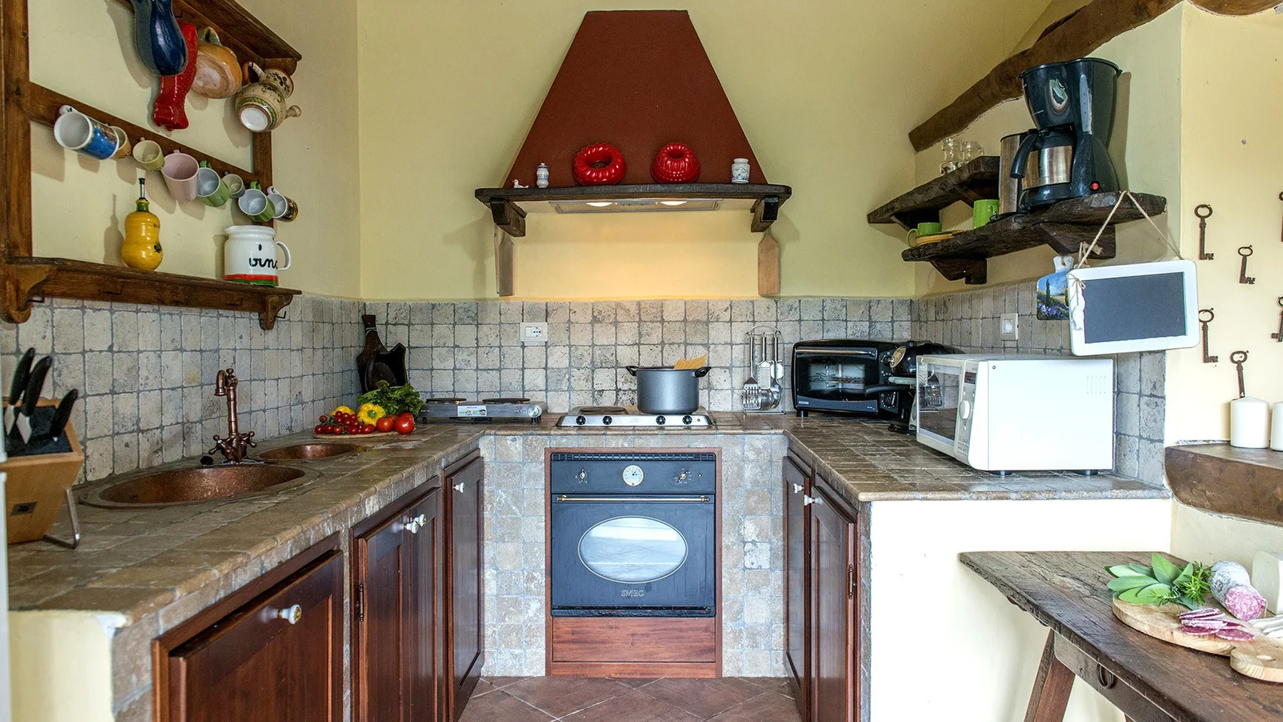 A rustic kitchen with tiled walls, wooden cabinets, and a central oven.