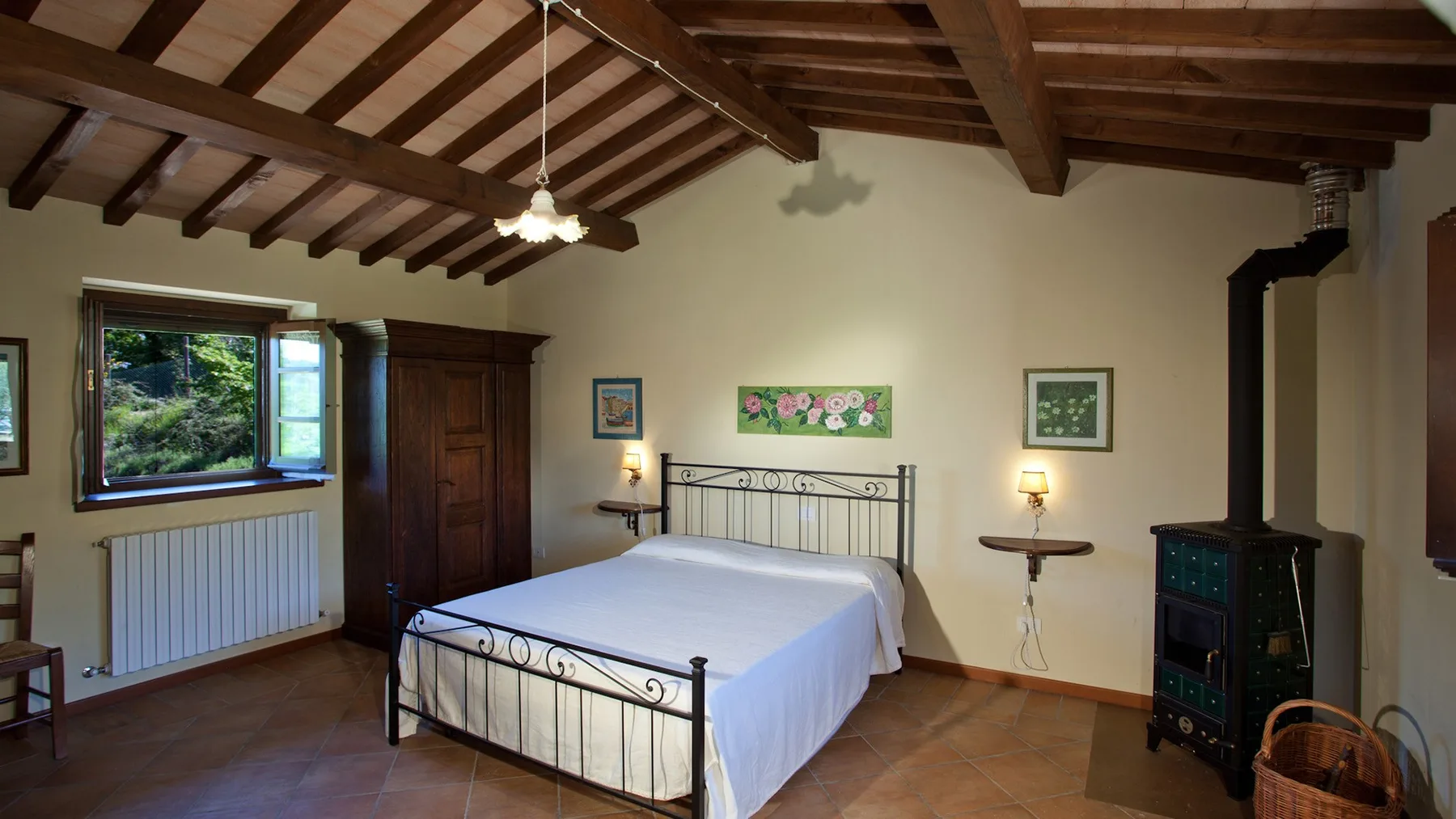 A bedroom with a metal-framed bed beneath exposed wooden ceiling beams.