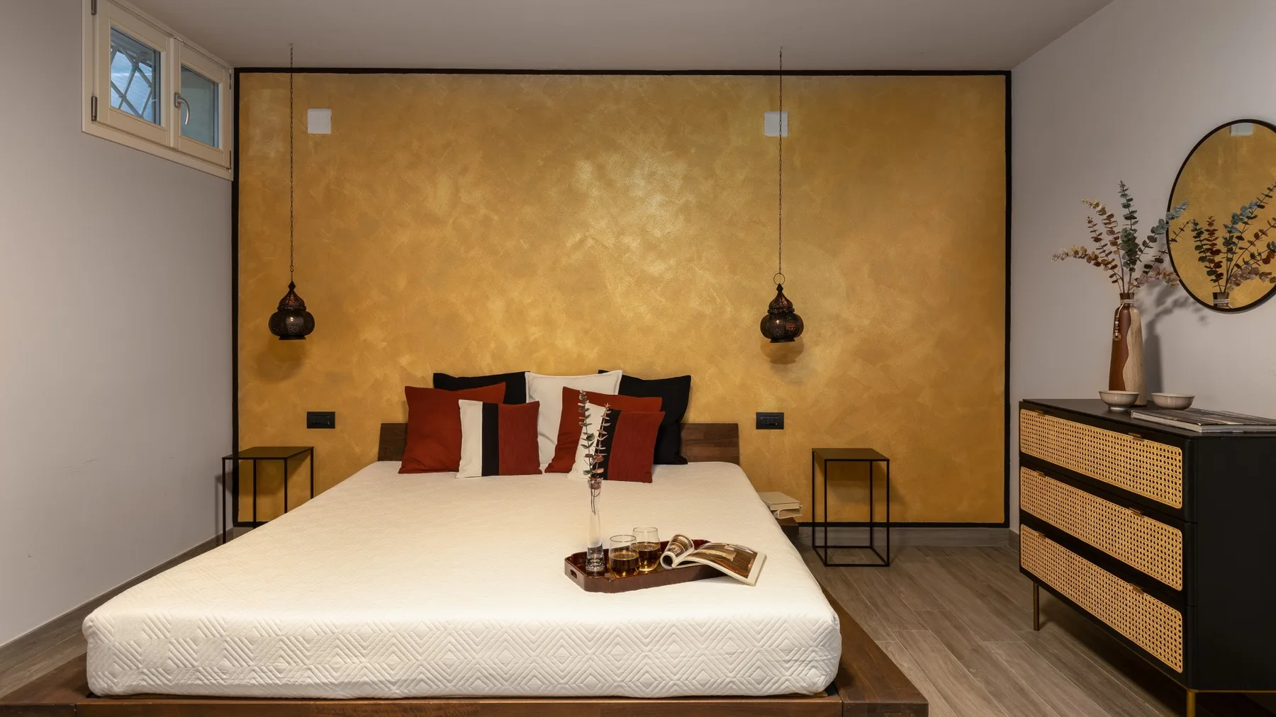 A bedroom with a large bed, warm gold accent wall, and bedside tables.