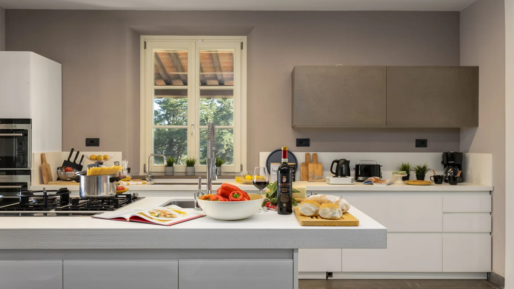 A modern kitchen with white cabinets, a central island, and a window.