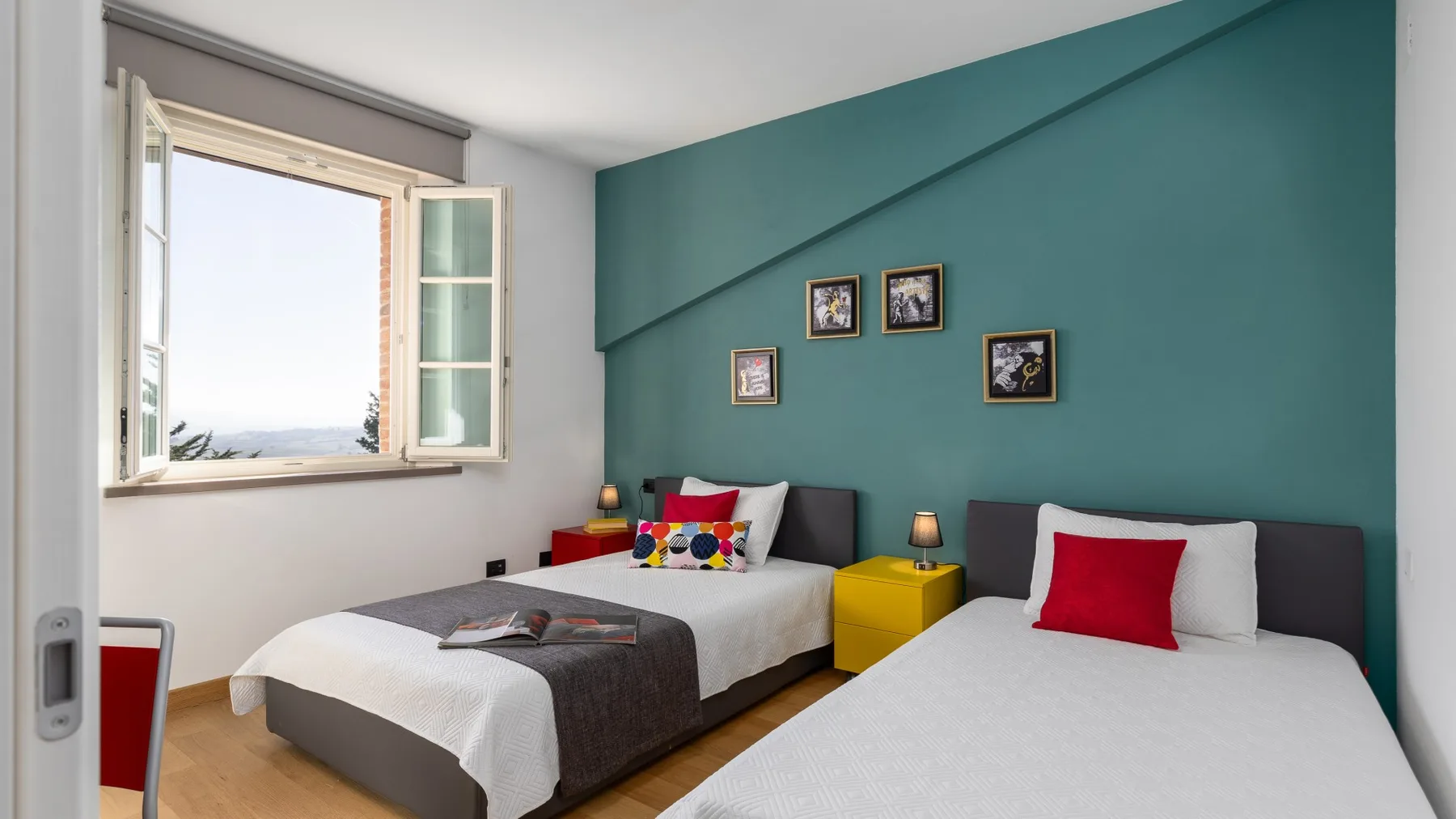 A bedroom with two beds and a teal accent wall.
