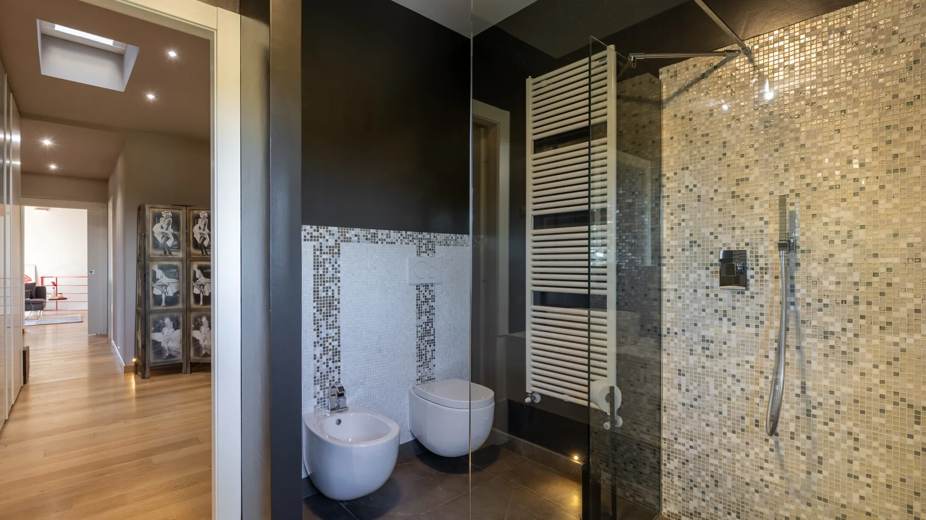 A modern bathroom with a glass shower and wall-mounted fixtures.