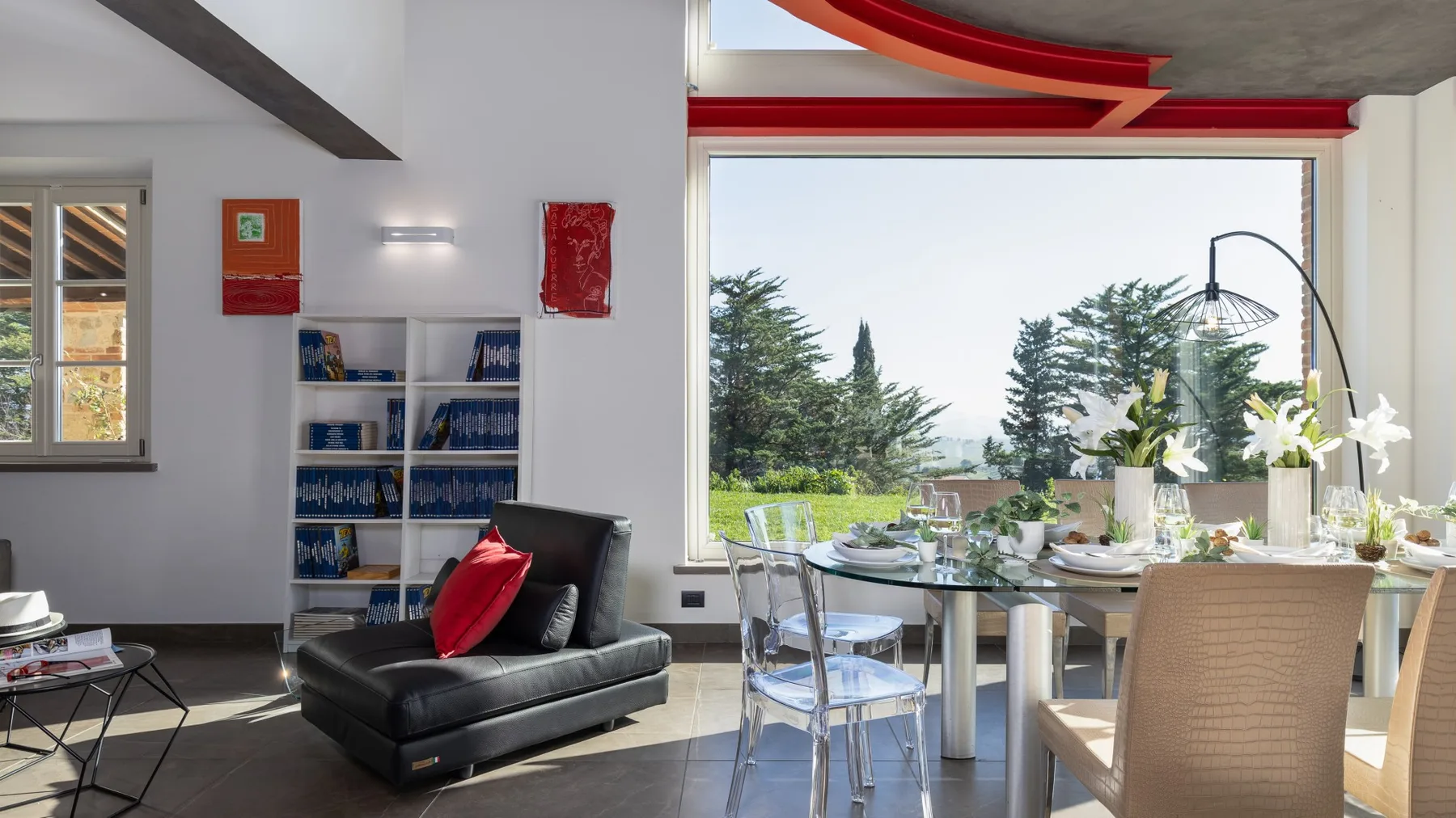 A bright dining area with a table beside a large window overlooking greenery.