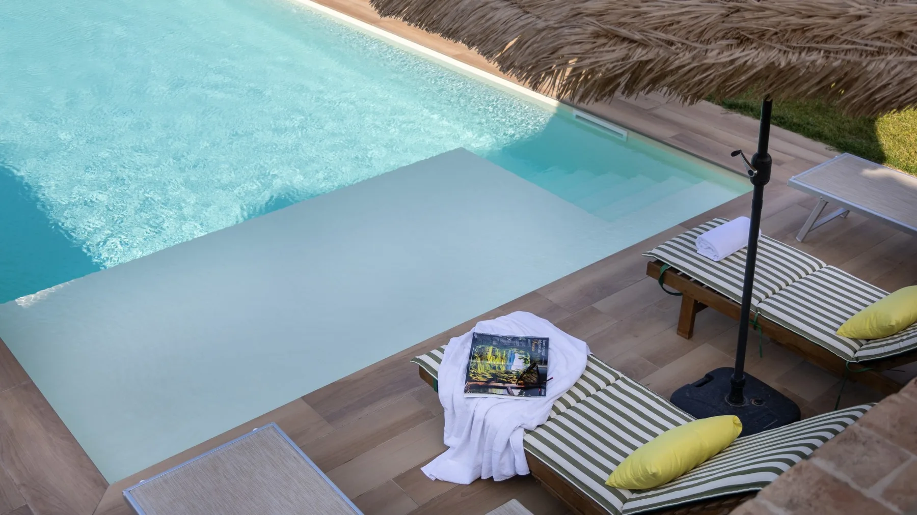 A poolside seating area with striped loungers beside the water.