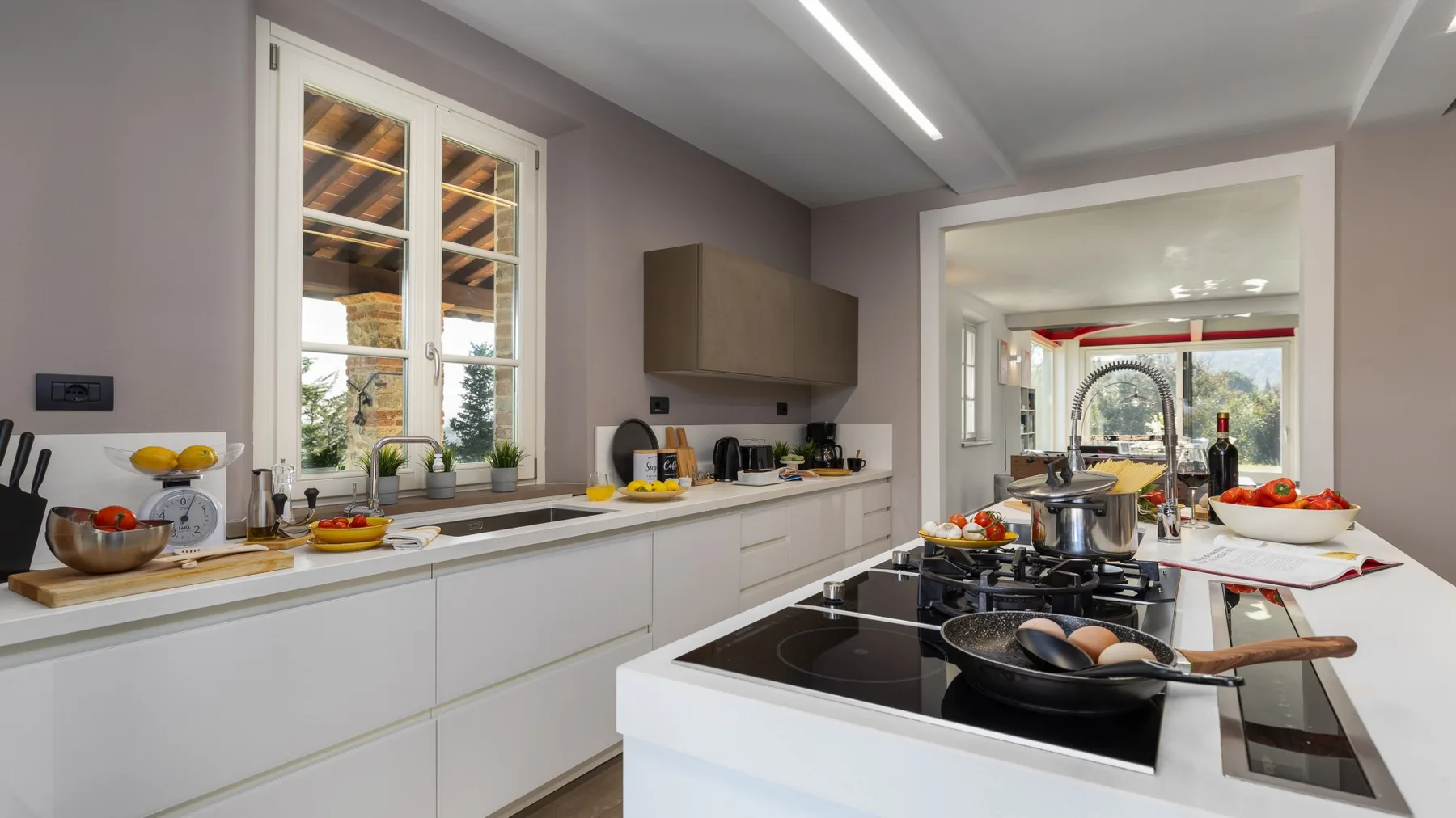 A bright kitchen with white cabinets and a central island with a cooktop.
