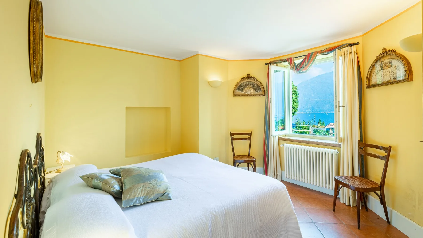 Un dormitorio con una cama junto a una ventana con vistas a un paisaje verde.