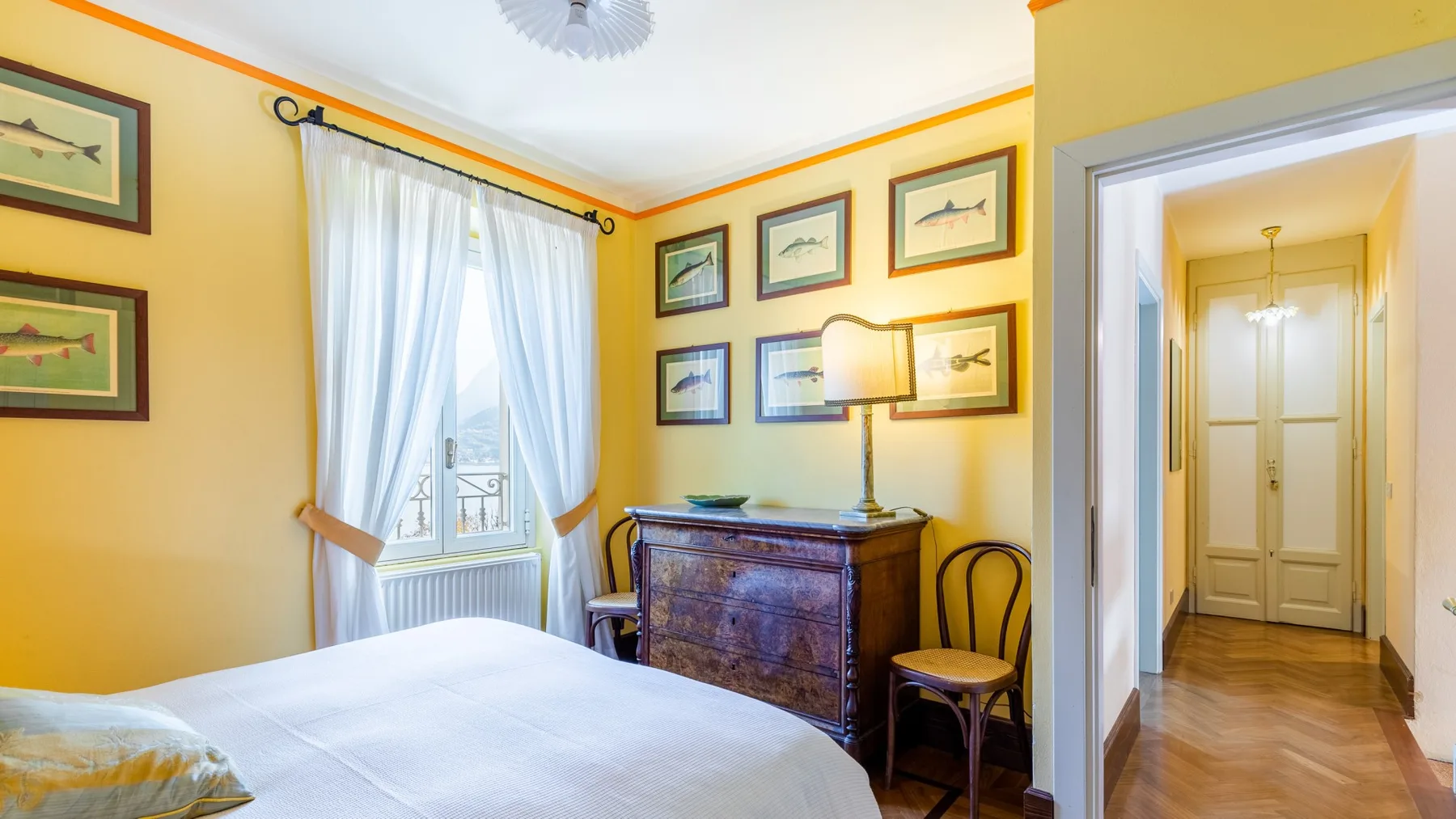 Un dormitorio con una cama, una ventana con cortinas y una cómoda de madera.