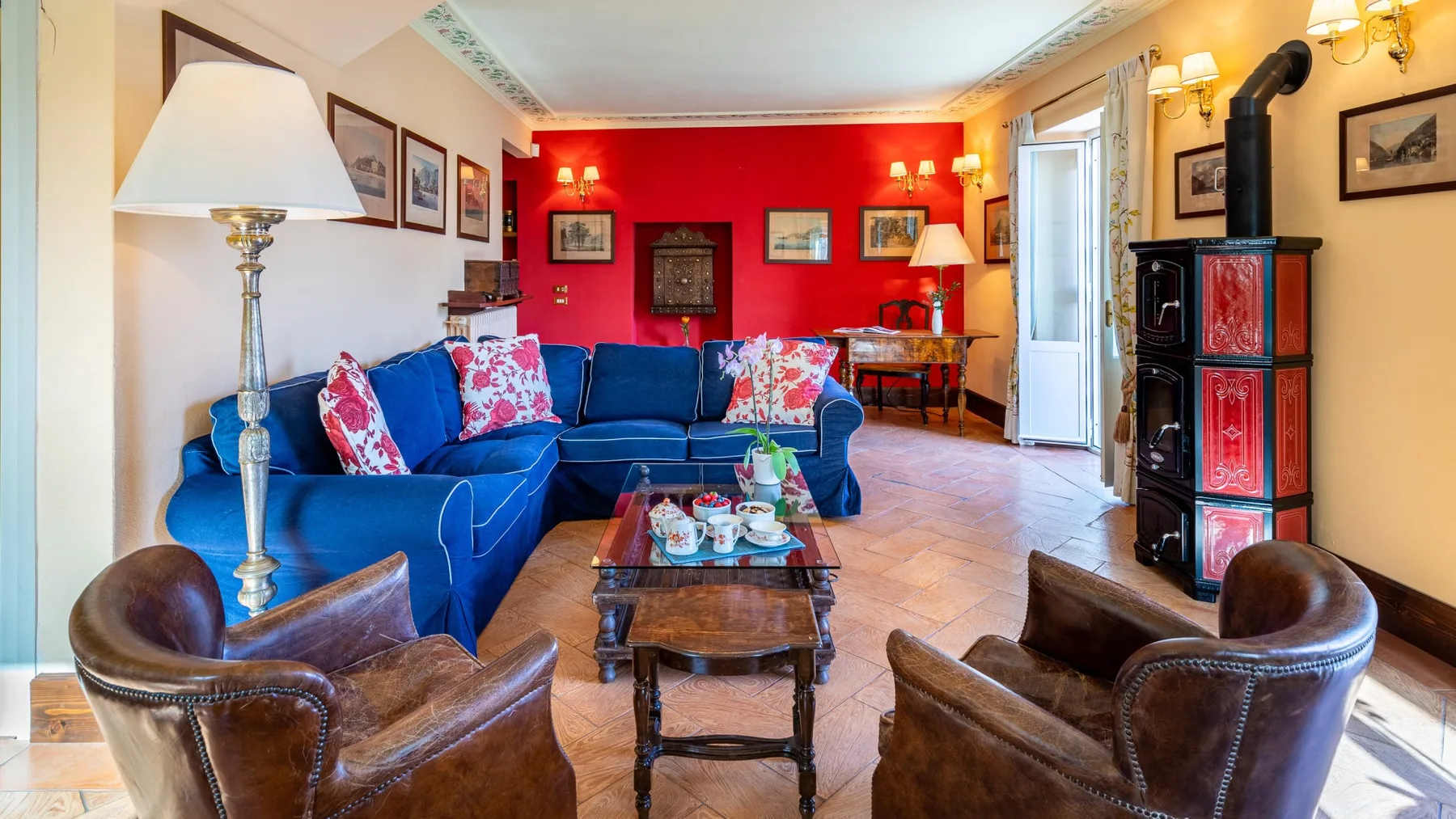 Una sala colorida tiene asientos azules, sillones marrones y una pared roja.