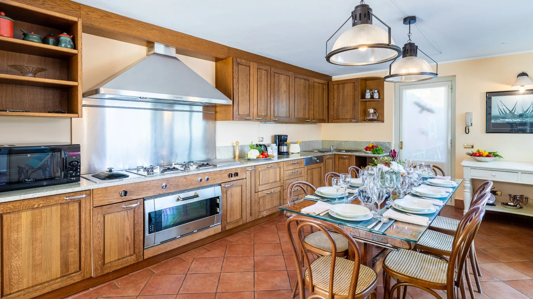 Una cocina amplia con gabinetes de madera, electrodomésticos de acero inoxidable y una mesa de comedor.