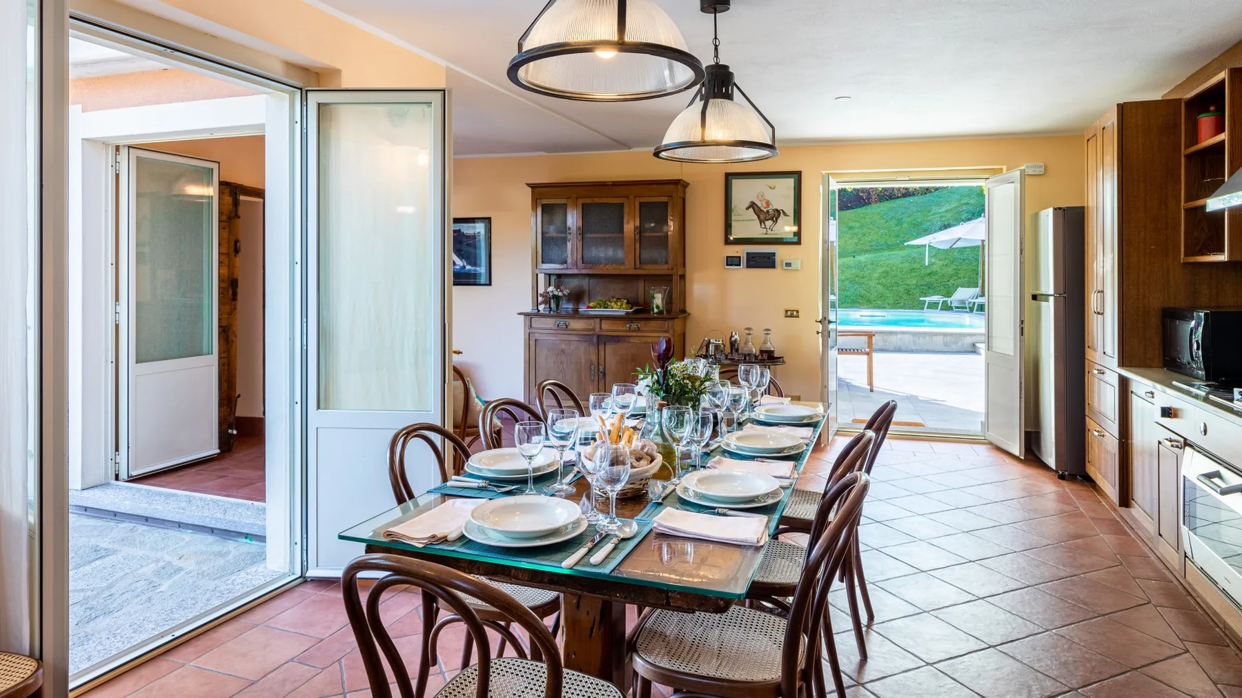 Comedor con una mesa larga puesta junto a puertas abiertas al patio.
