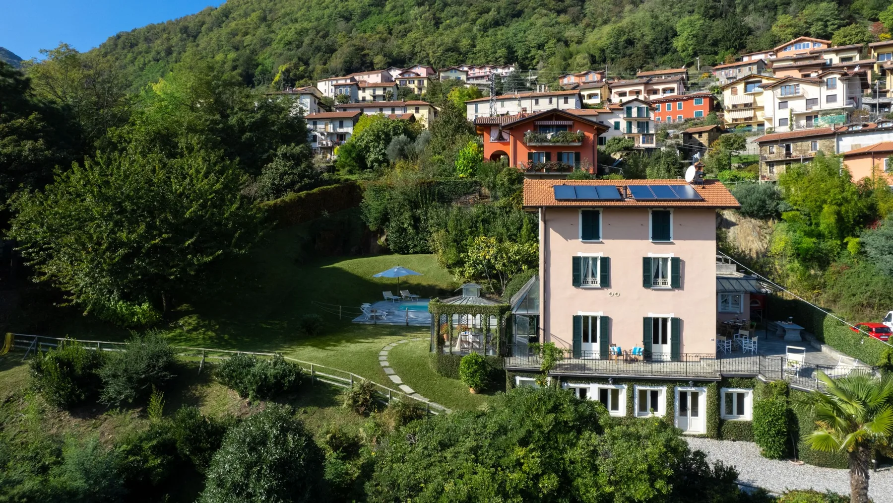 Una escena residencial en una ladera, con una casa rosada entre árboles y vegetación.