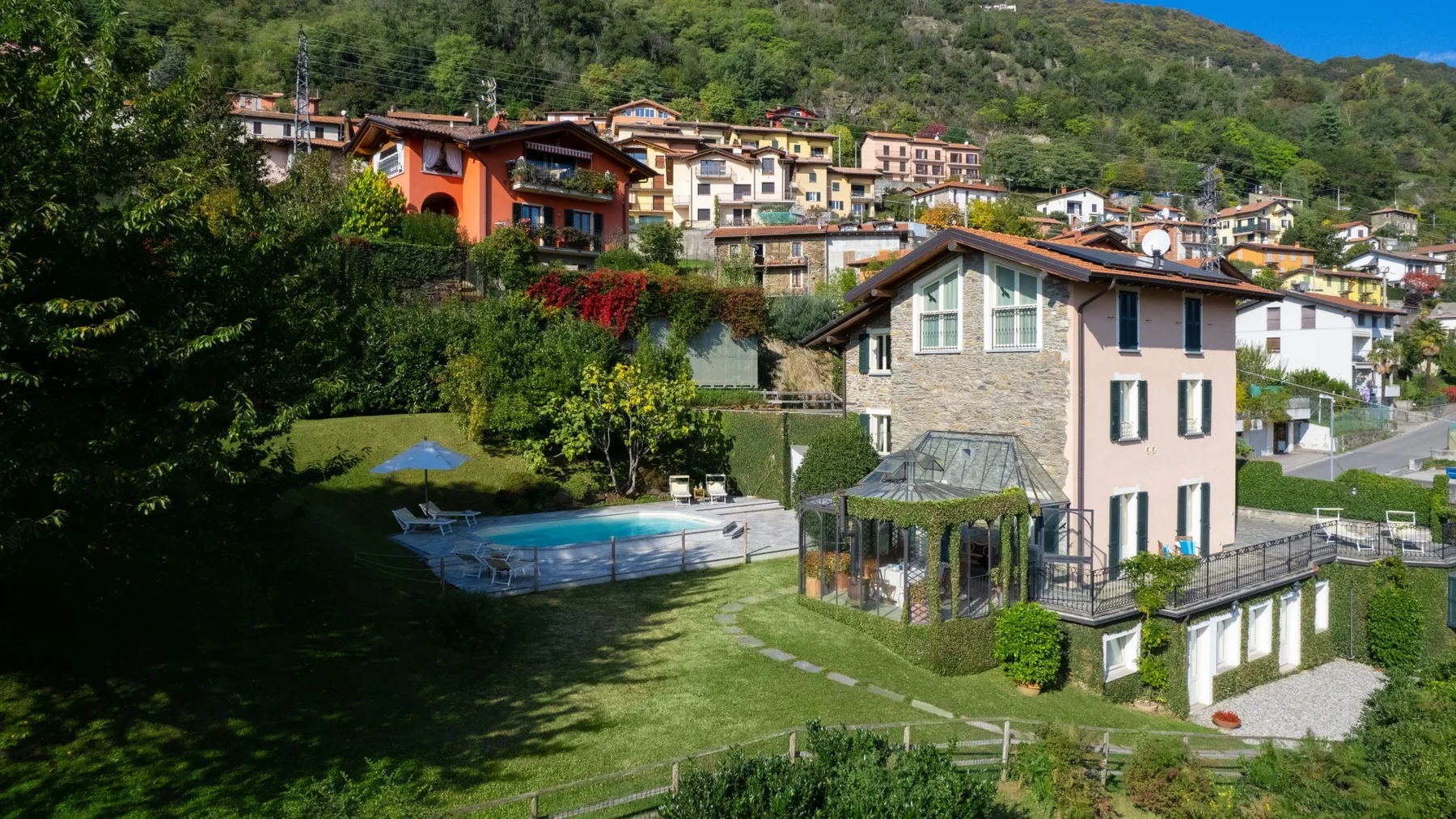Una zona residencial en la ladera con una casa clara junto a un jardín y una piscina.
