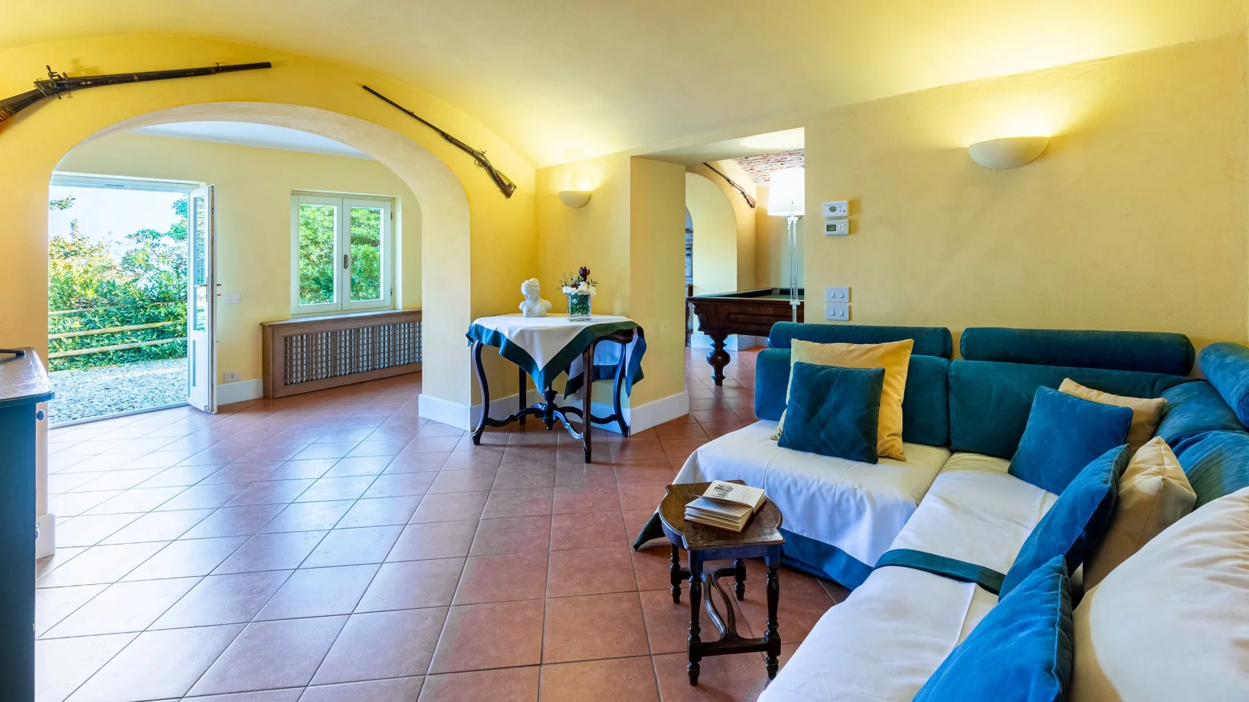 Una sala luminosa con asientos azules y una pequeña mesa junto a la puerta abierta.