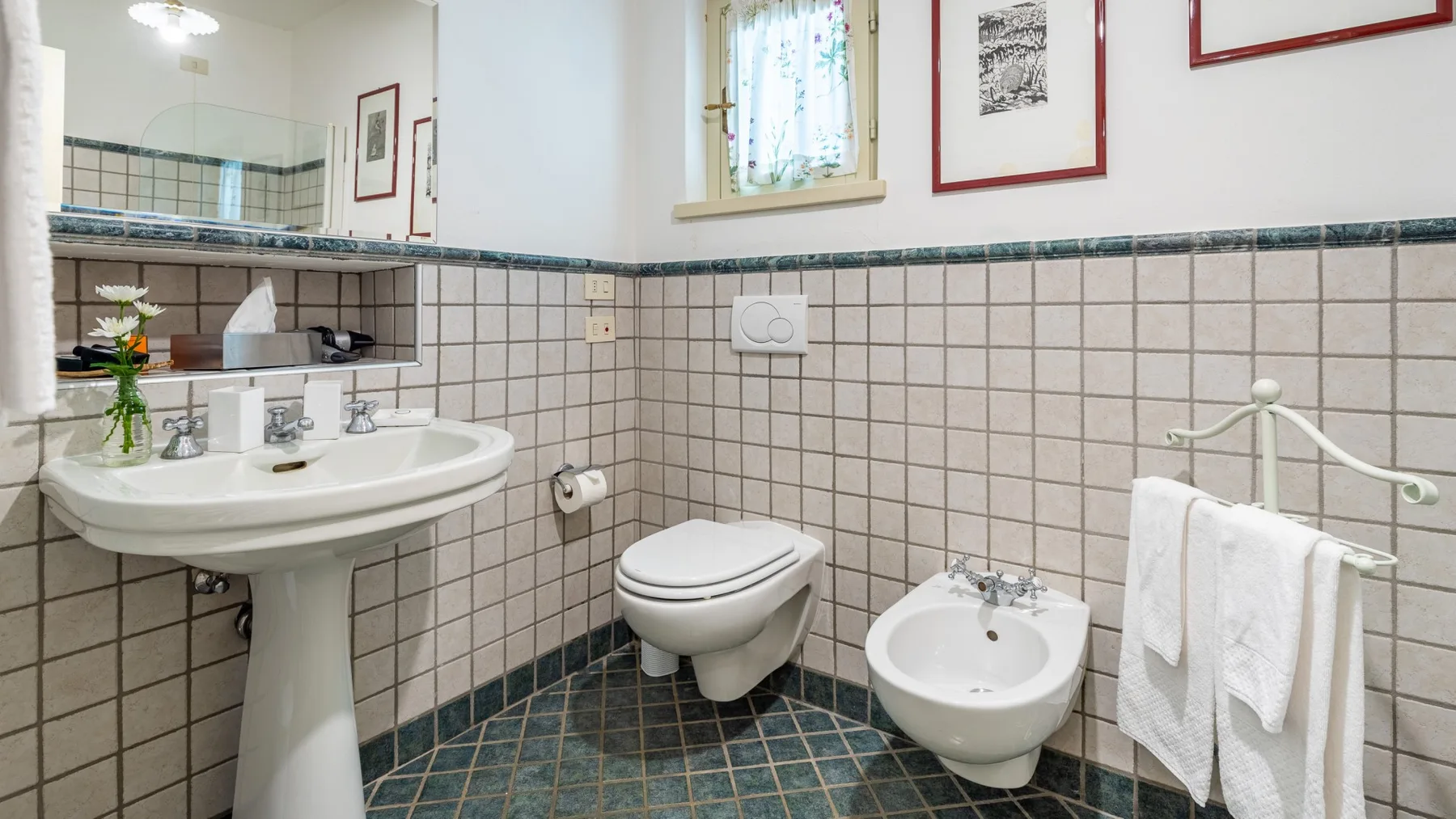 Un baño alicatado con lavabo, inodoro, bidé y toallas.