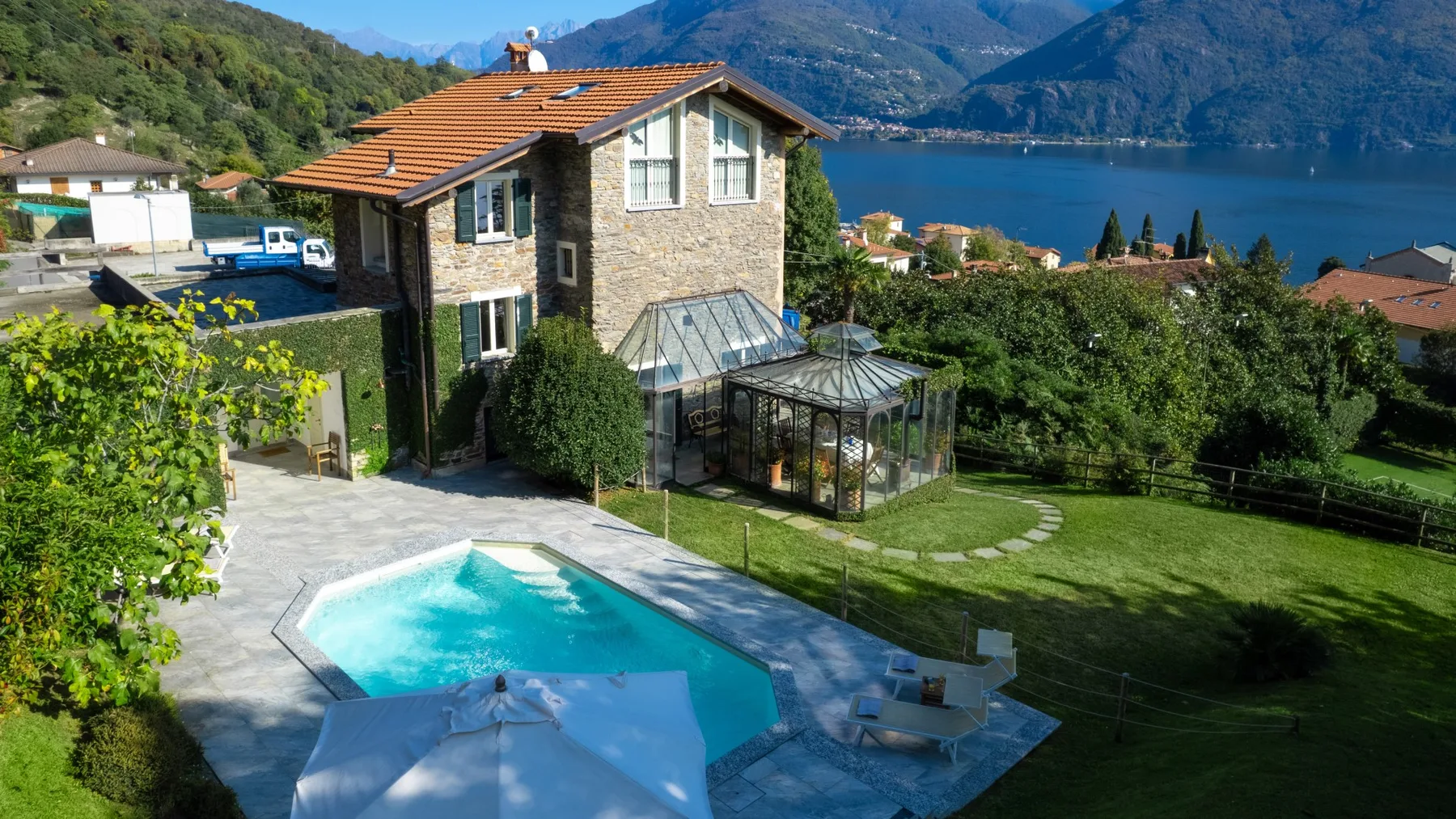 Una casa de piedra da a una piscina, un jardín y un lago.