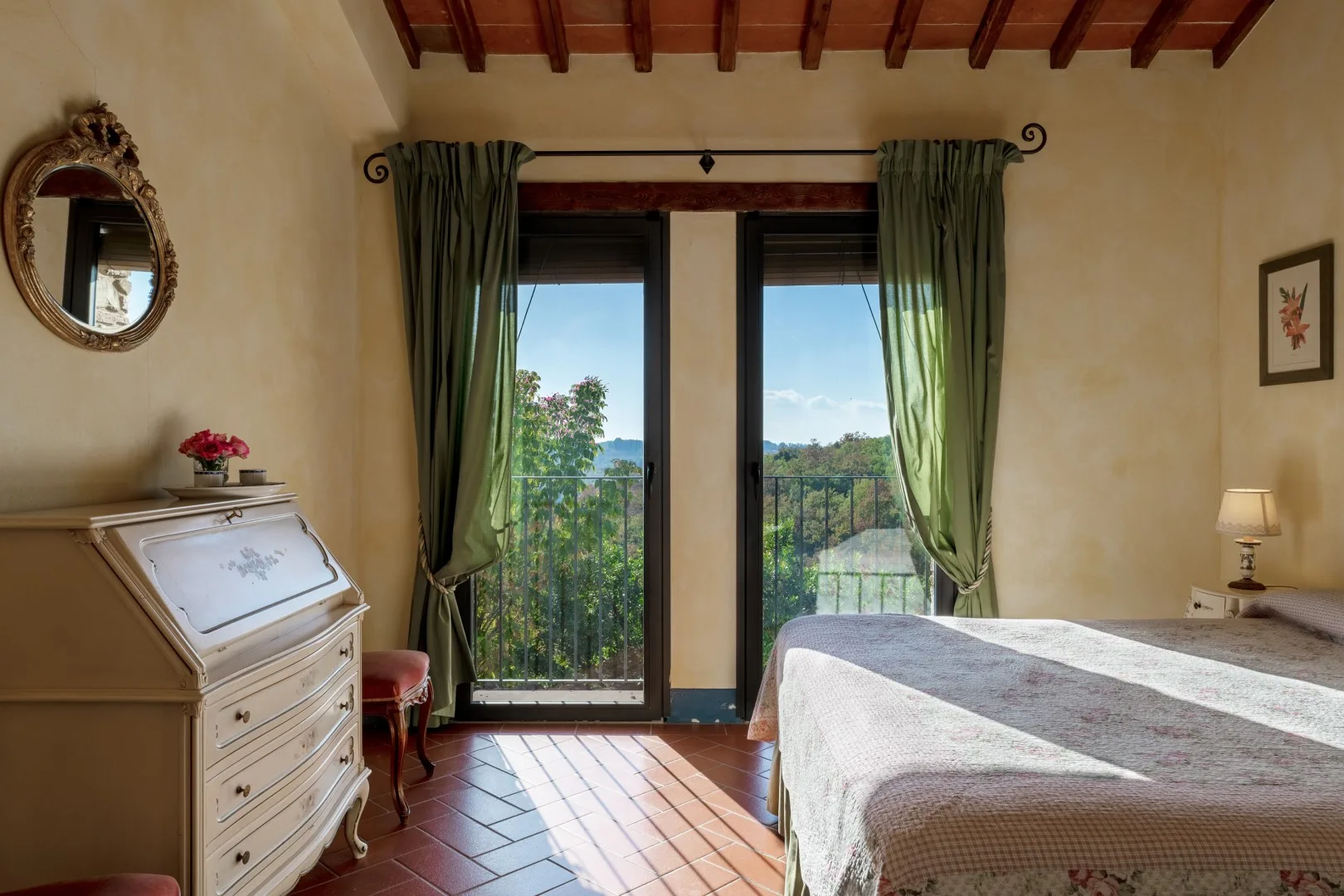 Un dormitorio con cama doble, cómoda blanca y puertas acristaladas que dan a un balcón.