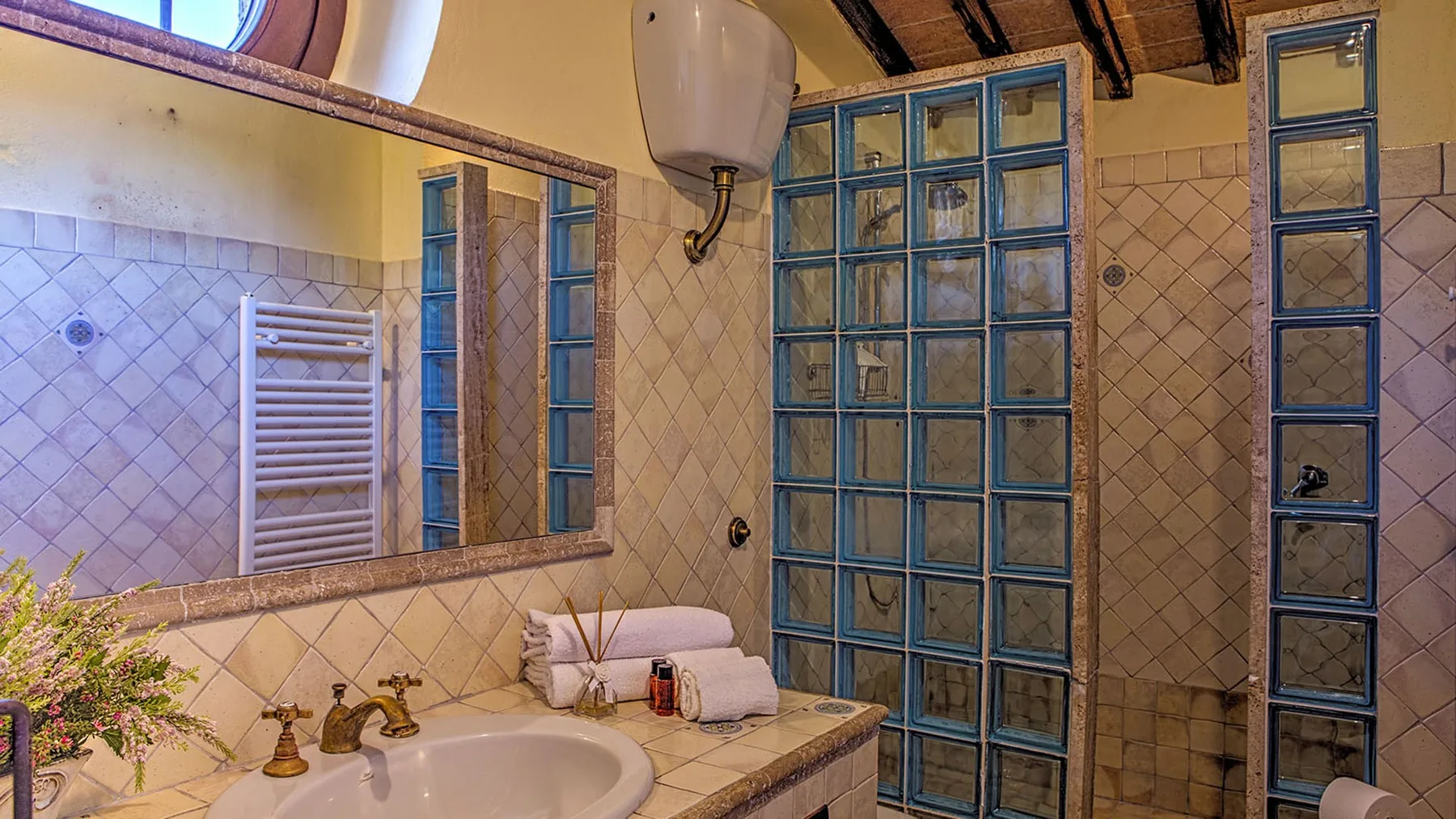 A tiled bathroom features a white sink, wall-mounted towel rack, and blue-framed glass-block windows.