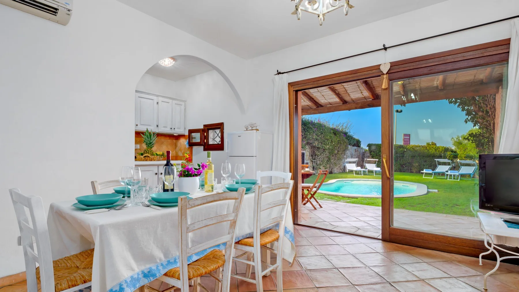 Un comedor da a un patio y un jardín con piscina.