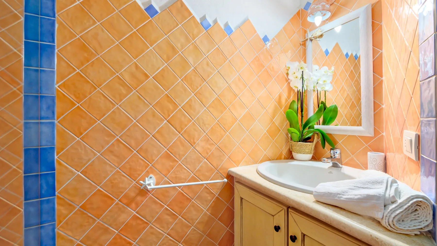 Un baño con azulejos, lavabo con mueble y una toalla doblada.