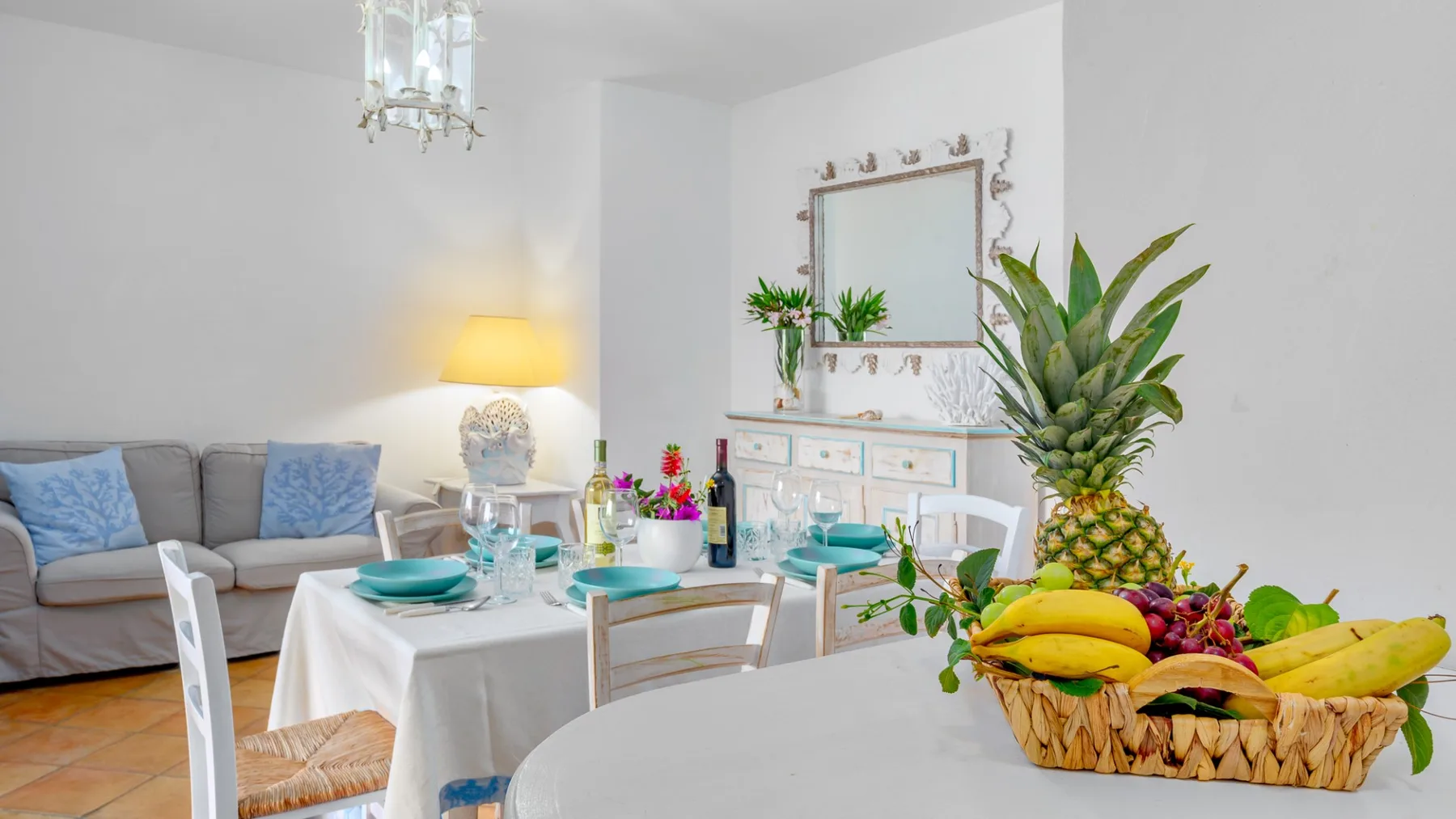 Un comedor con una mesa puesta junto a un sofá y una cesta de fruta.