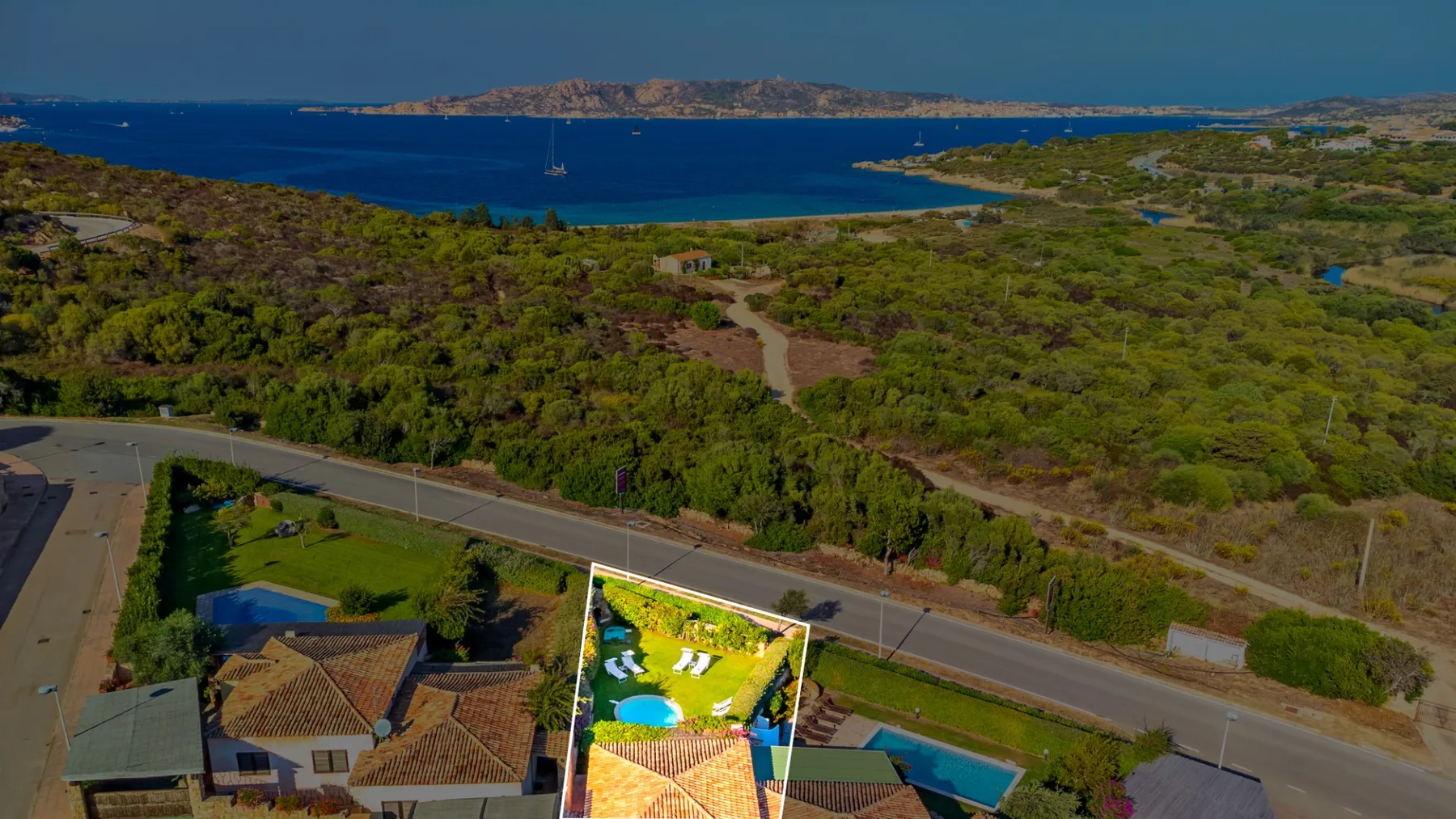 Una vista aérea muestra un paisaje costero, con una carretera y casas en primer plano.