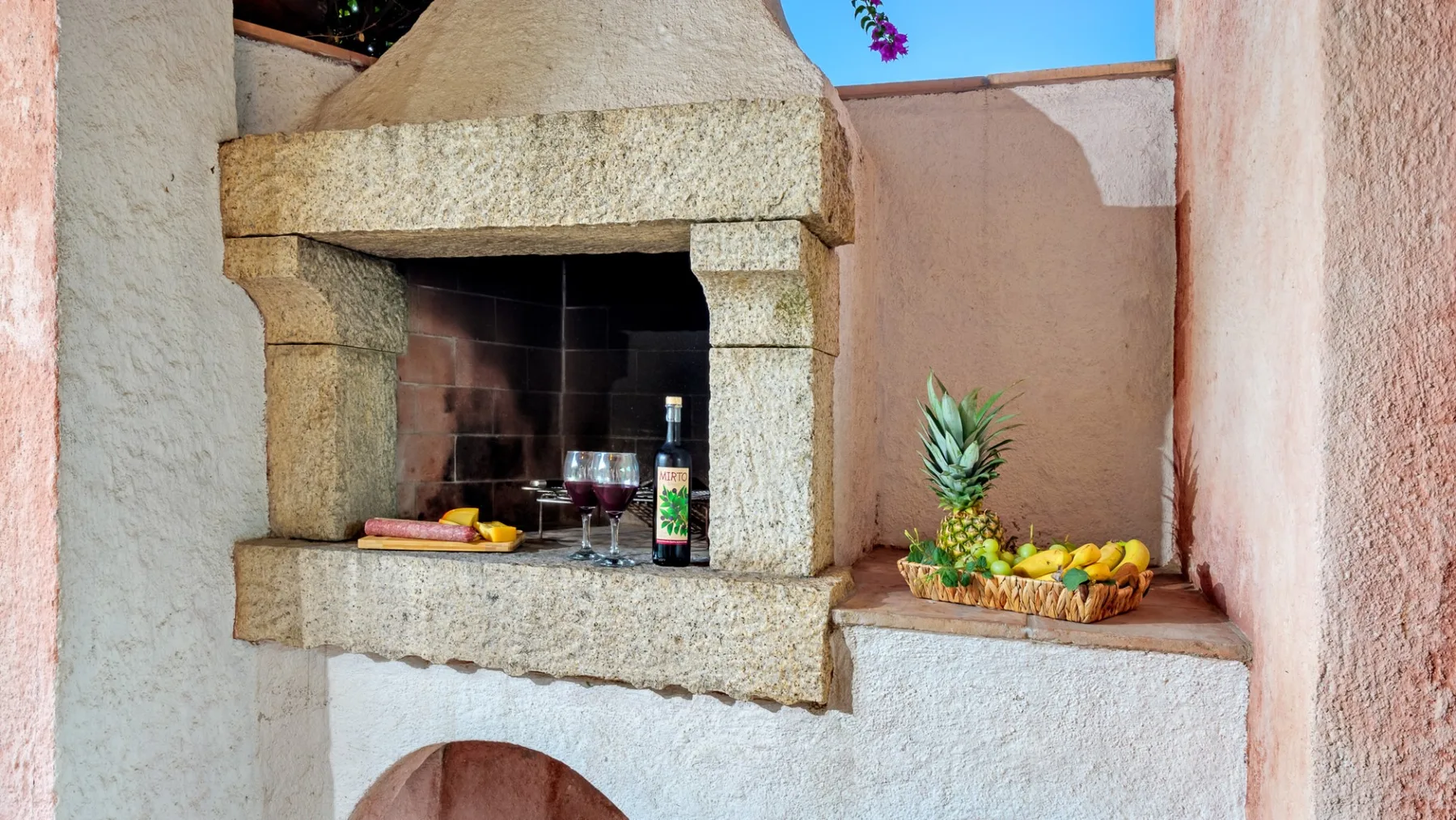 Una zona de cocina al aire libre con una barbacoa de piedra y fruta sobre la encimera.