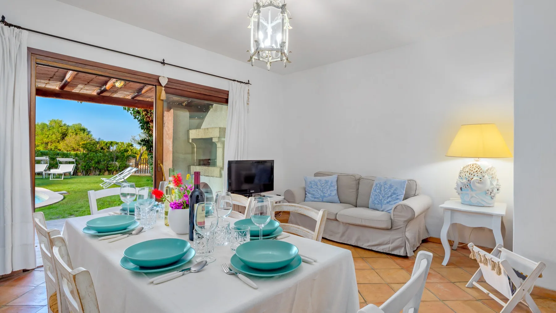 Comedor con una mesa preparada junto a una zona de estar y vistas al jardín.