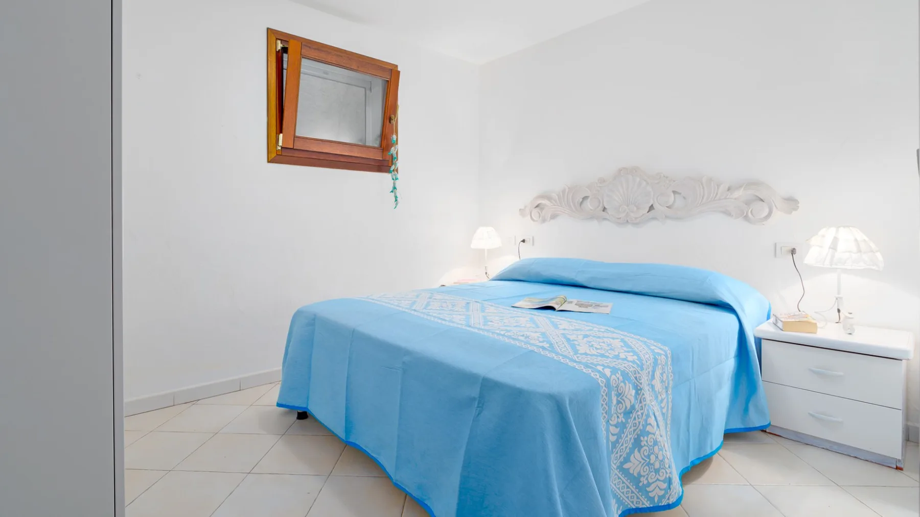 Un dormitorio con una cama cubierta con ropa de cama azul y una mesita de noche.