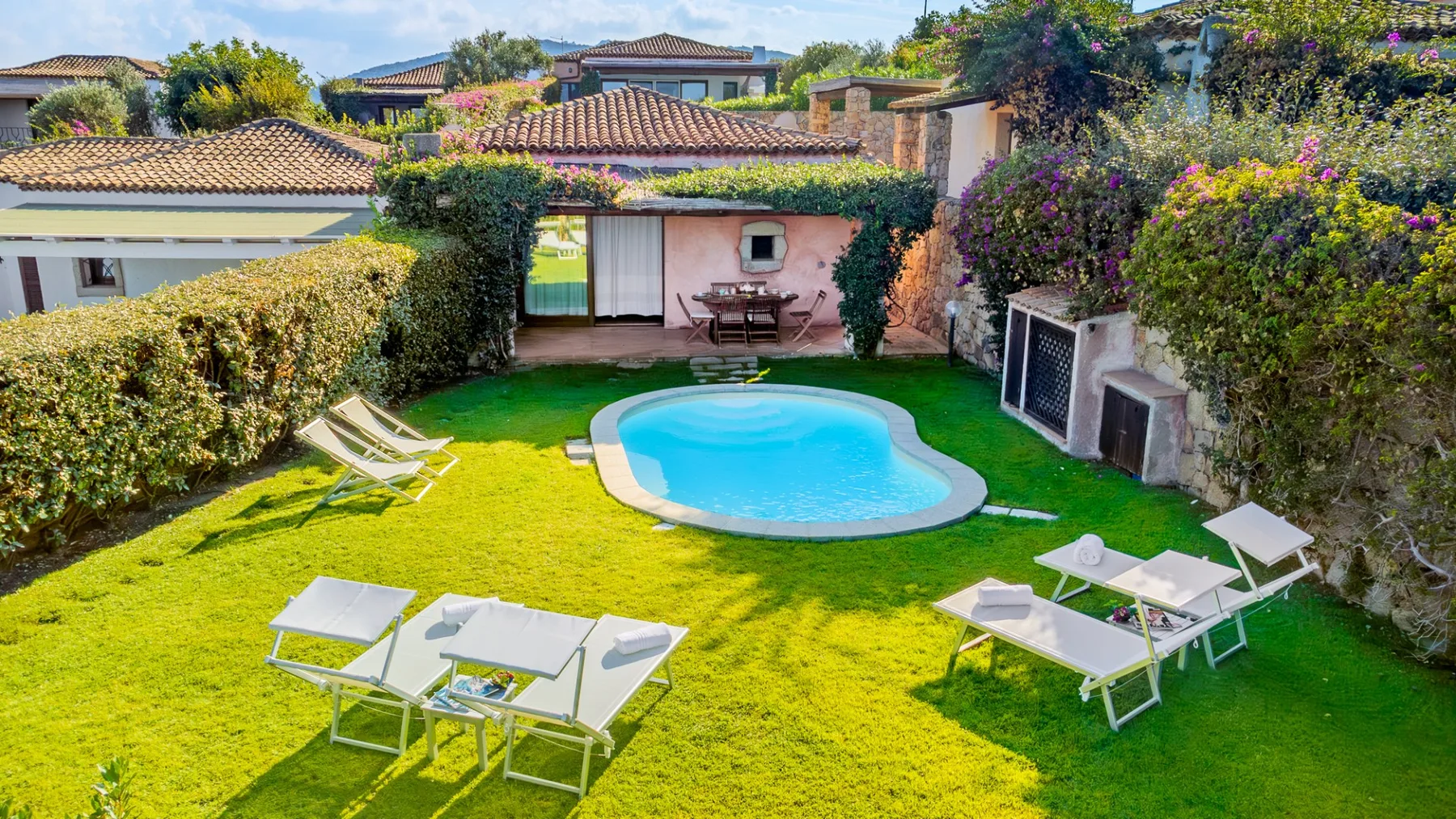 Un jardín con una pequeña piscina curva y asientos al aire libre.