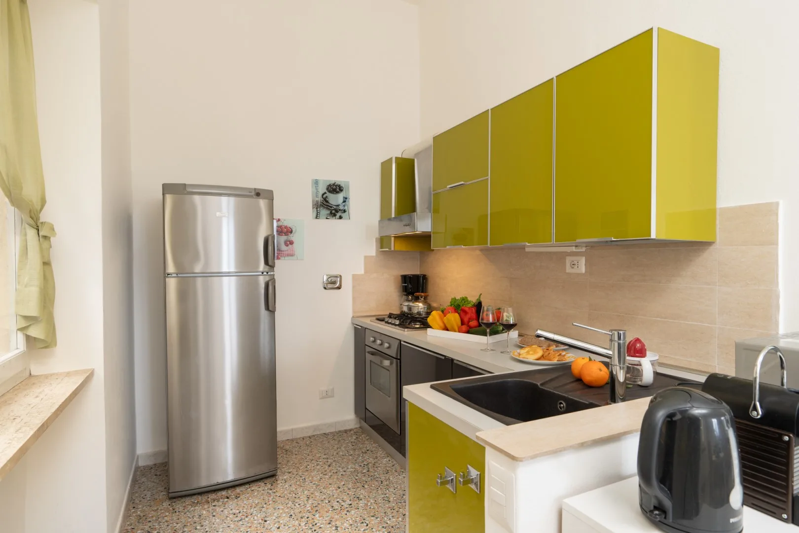 A bright kitchen with yellow cabinets, a refrigerator, and a countertop sink.