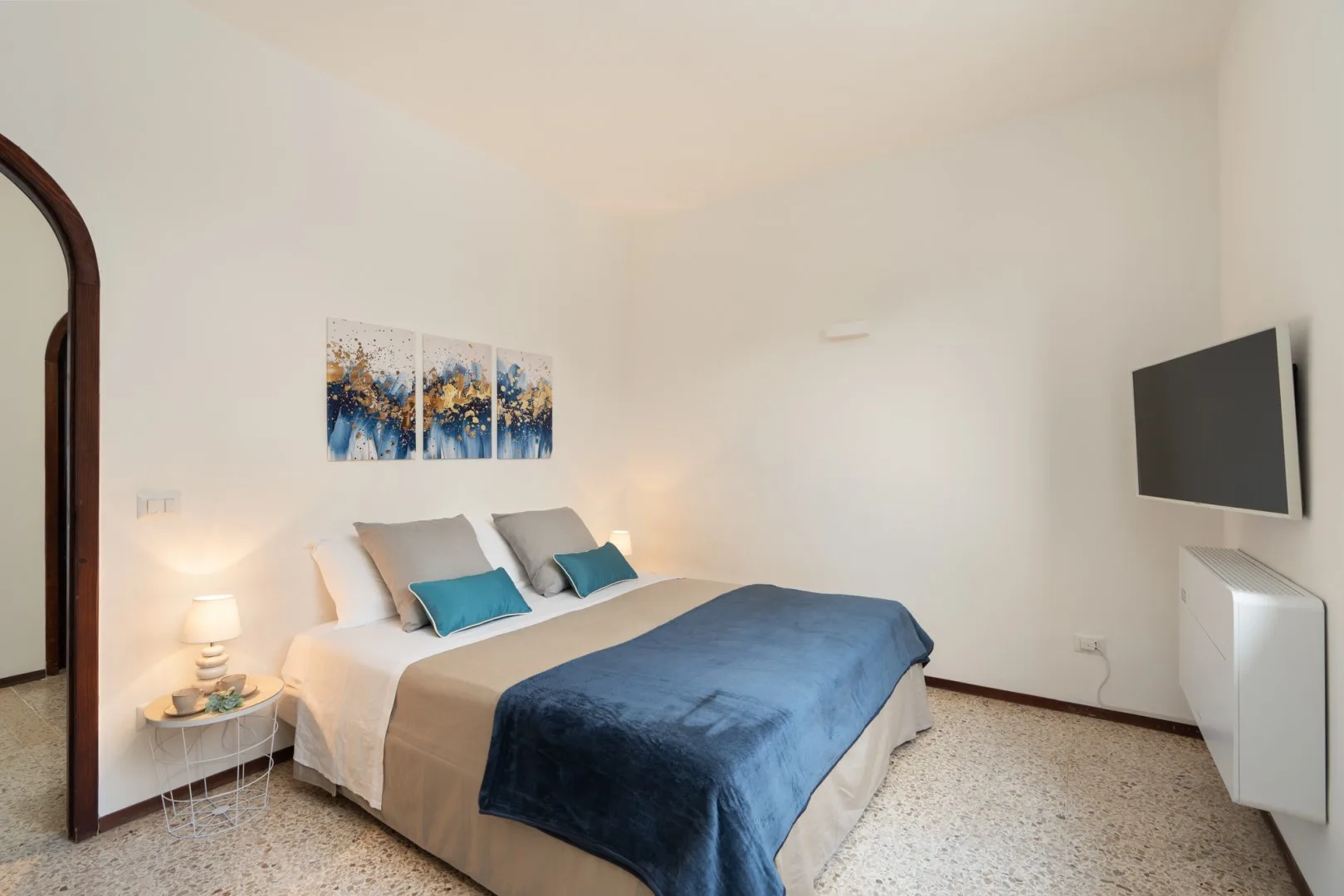 A bedroom with a neatly made bed and a wall-mounted television.