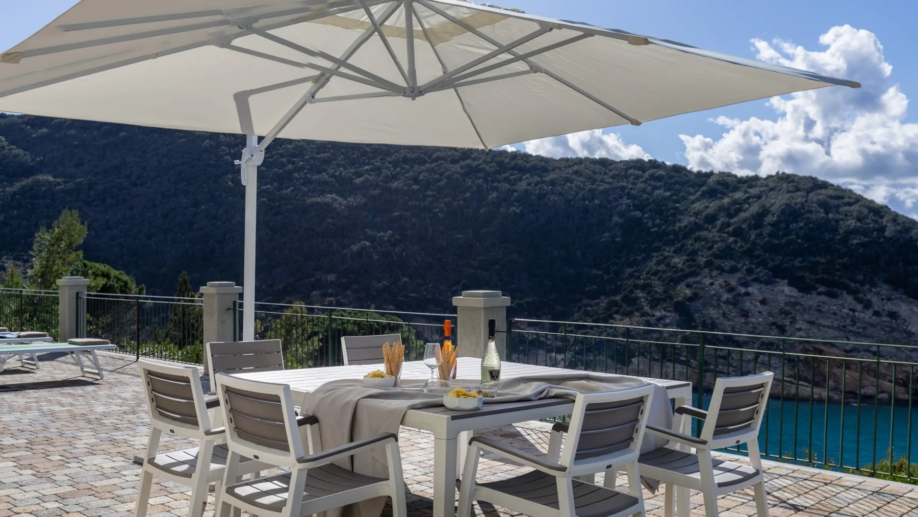 An outdoor dining area with a table and chairs beneath a large umbrella.