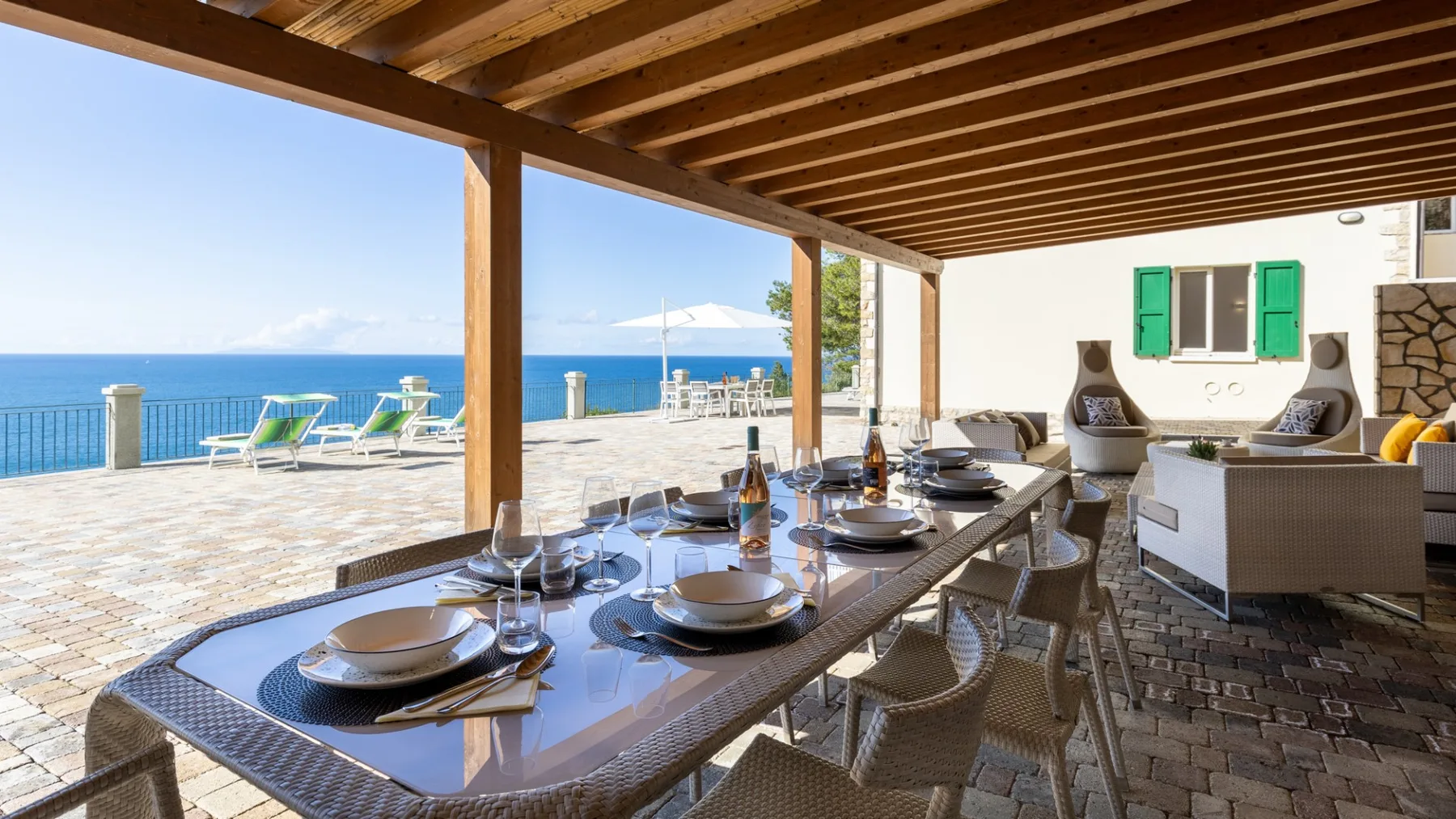 A covered outdoor dining area with a set table overlooking the sea.