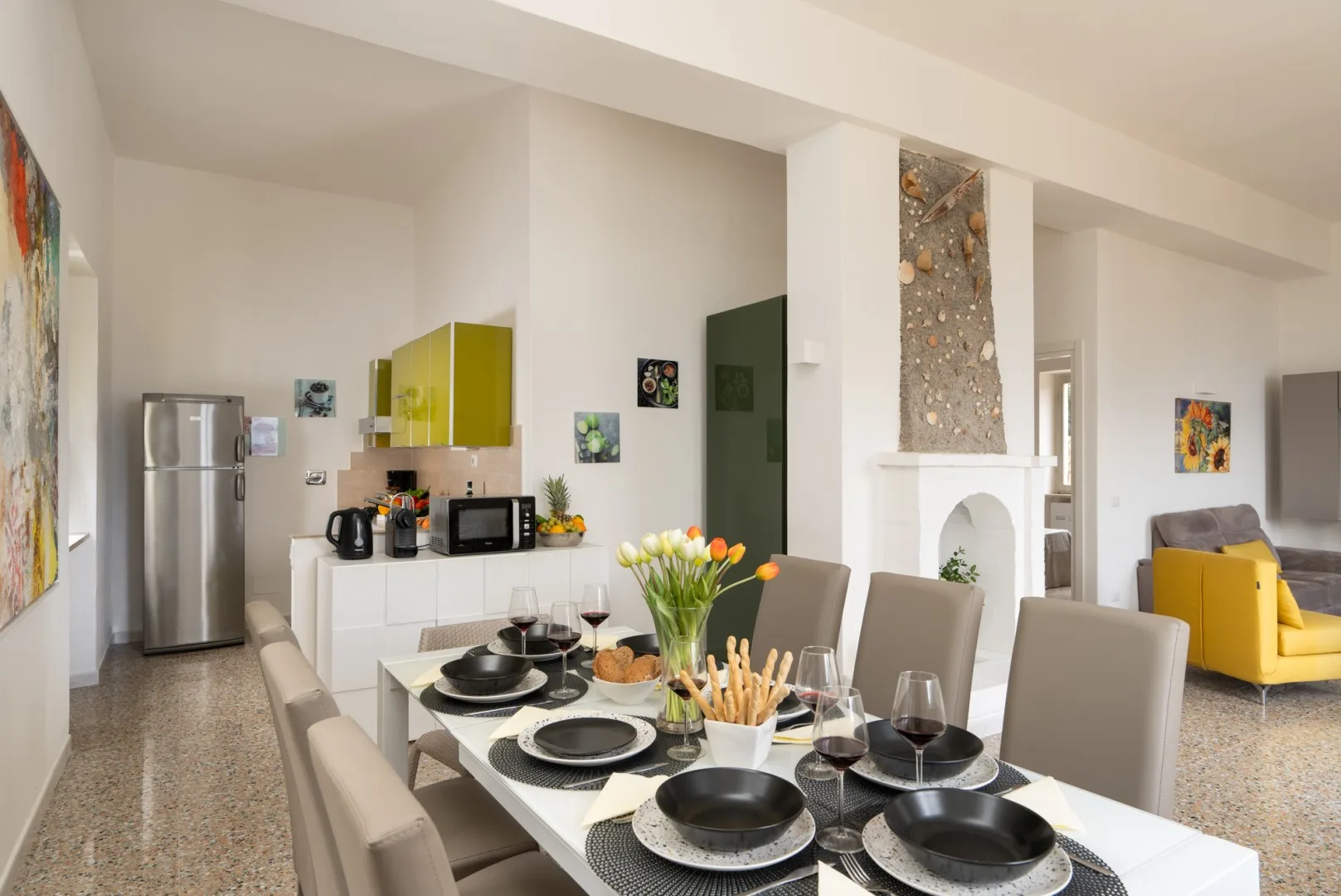 A dining area with a set table and a fireplace behind it.