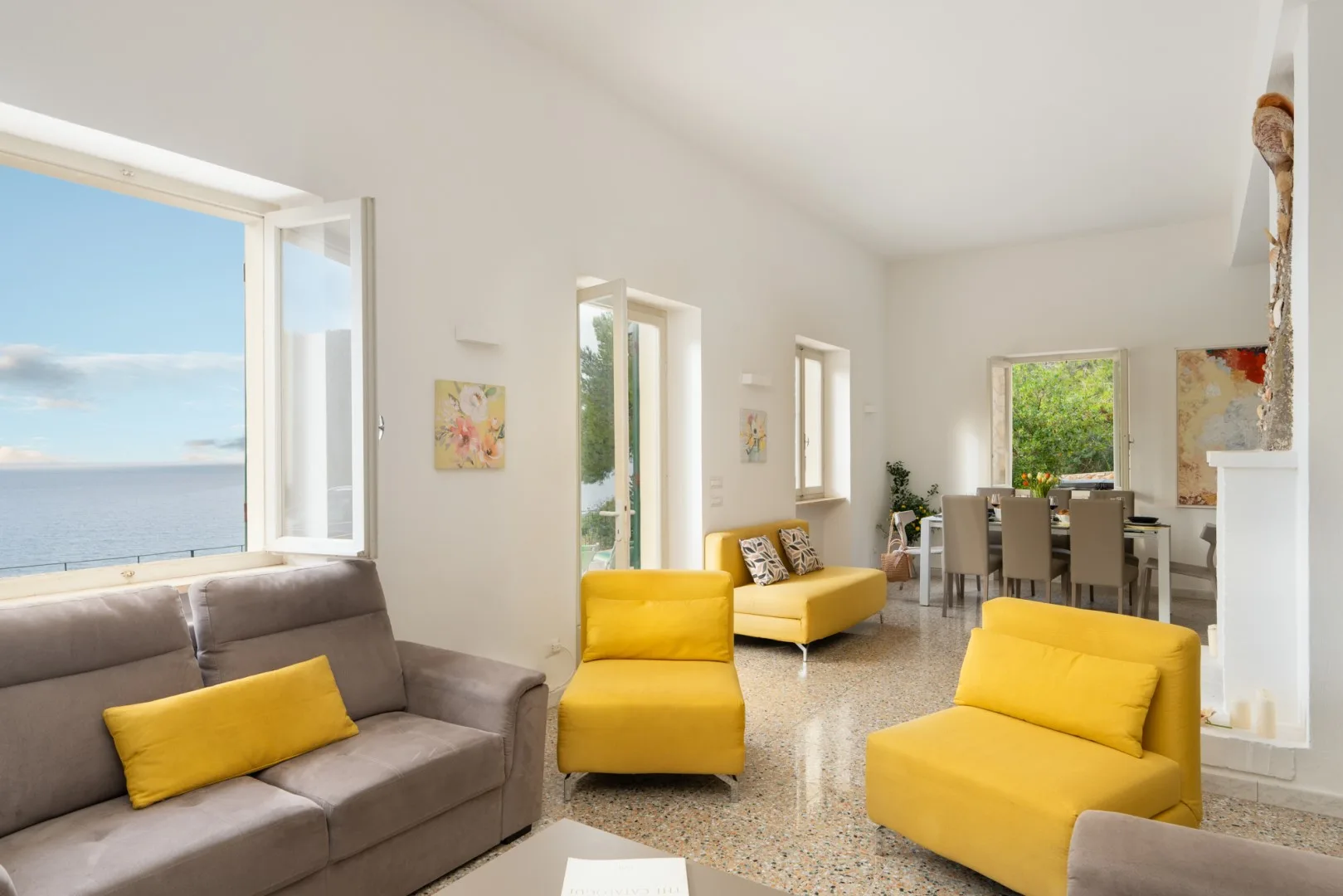 A bright living room with colorful seating and a dining area by the windows.