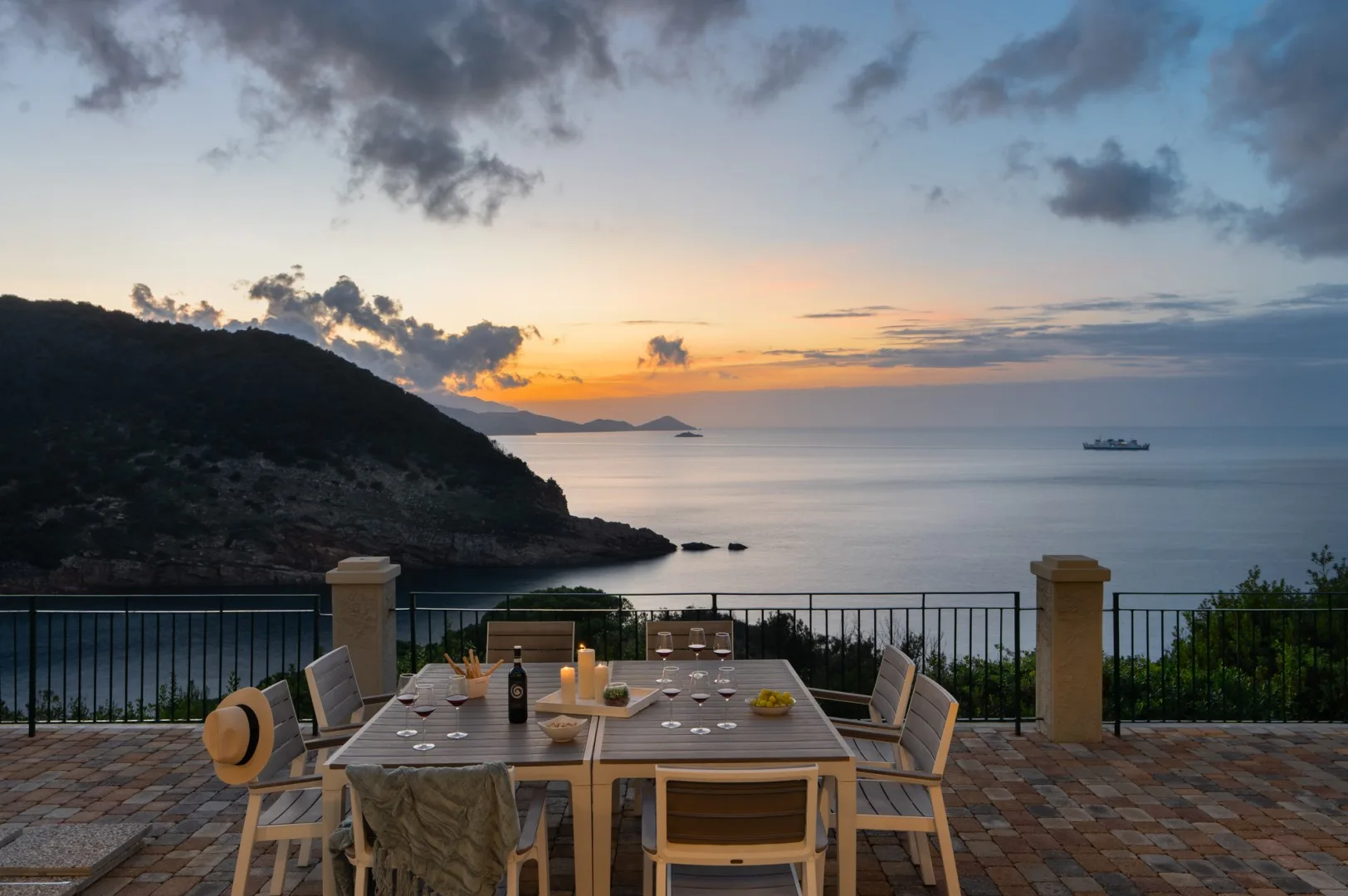 A patio dining area overlooks the sea at sunset.