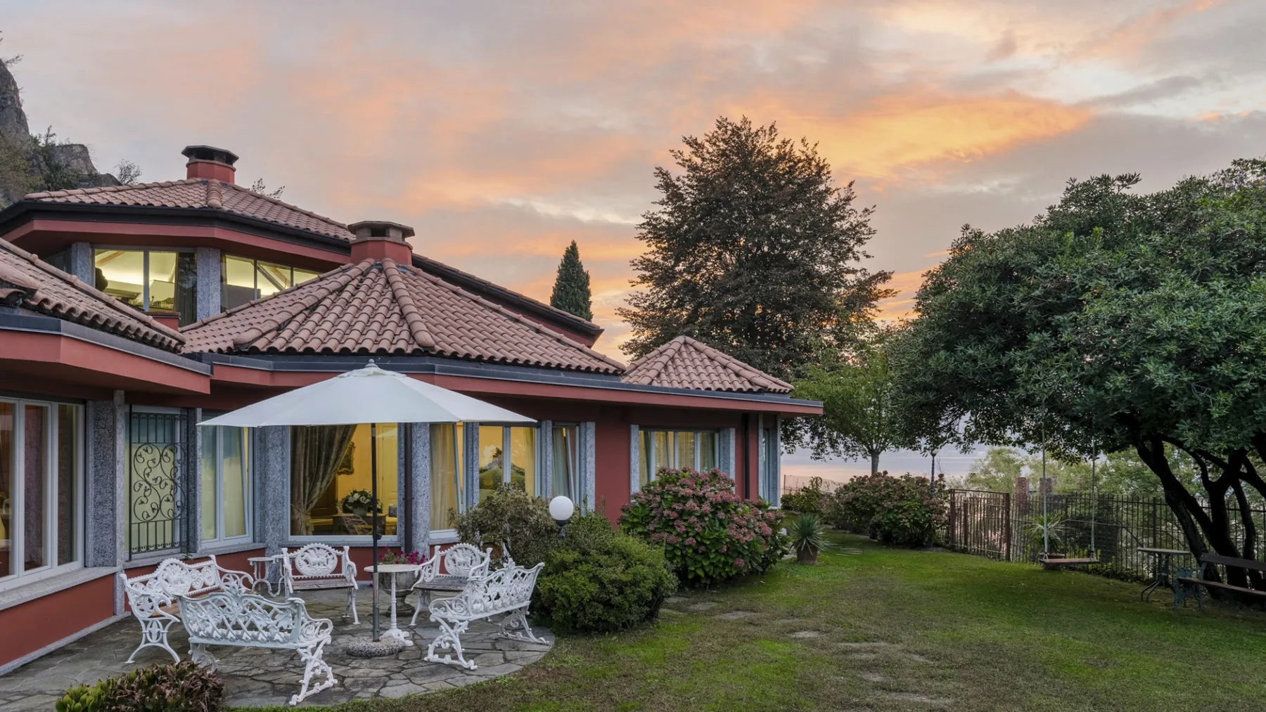 A house with a tiled roof and a garden seating area at sunset.