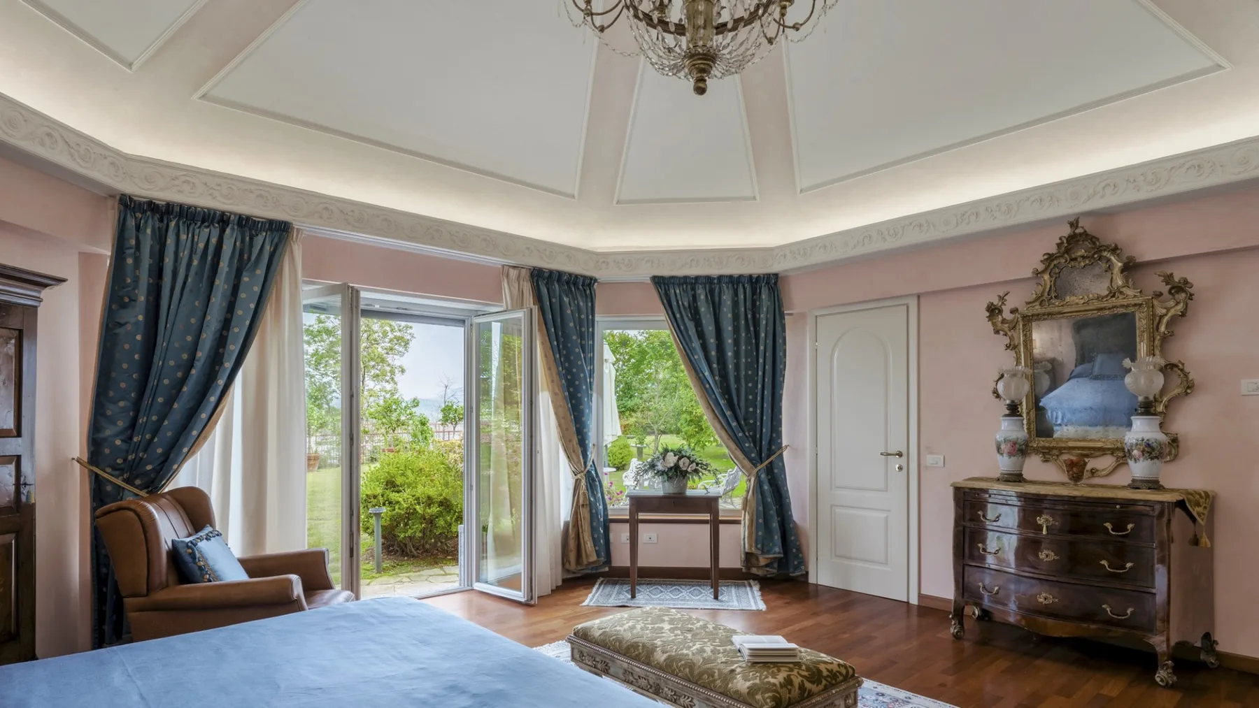 A bright sitting room with an armchair beside open doors to a garden.