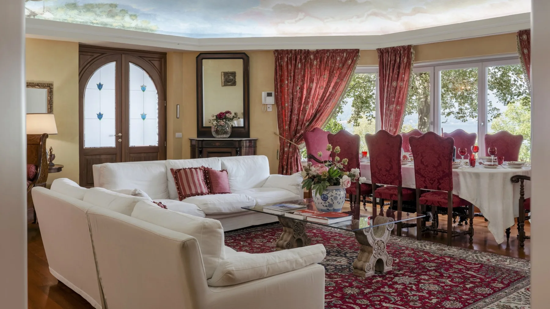 A living and dining room with white seating and a table beside large windows.