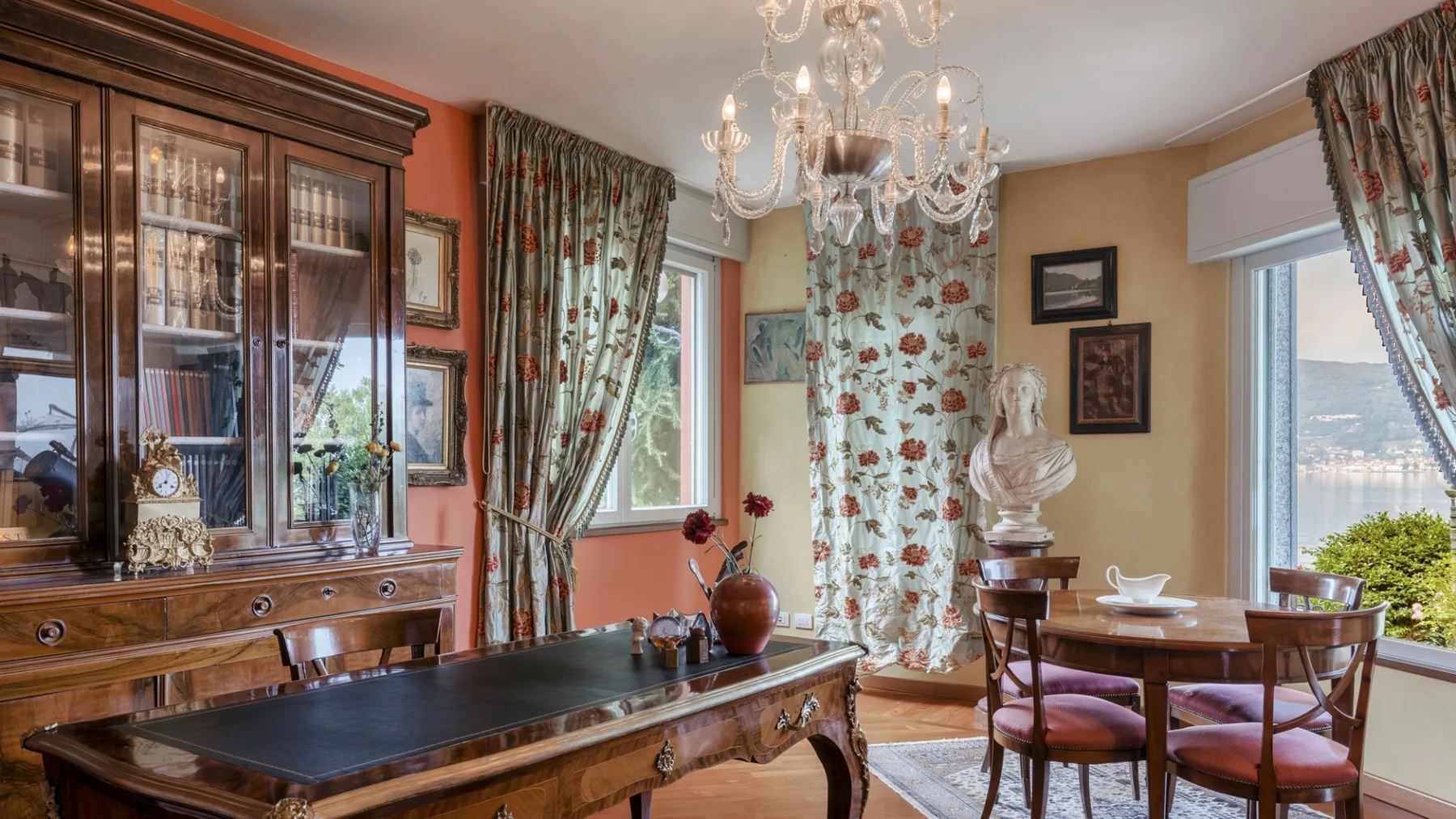 A formal dining room with a wooden table, upholstered chairs, and patterned curtains.