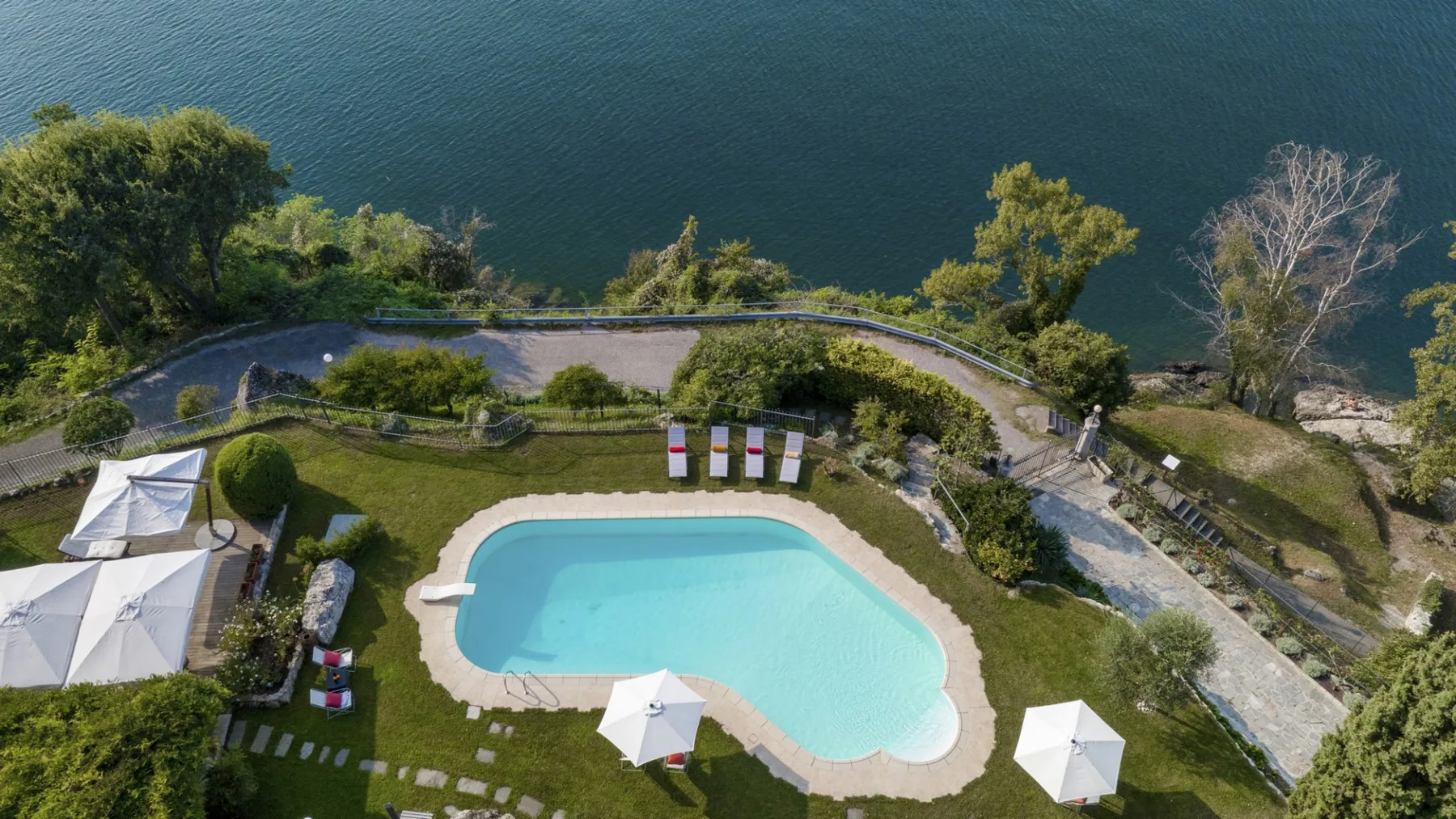 An aerial view of a swimming pool beside a landscaped shoreline.